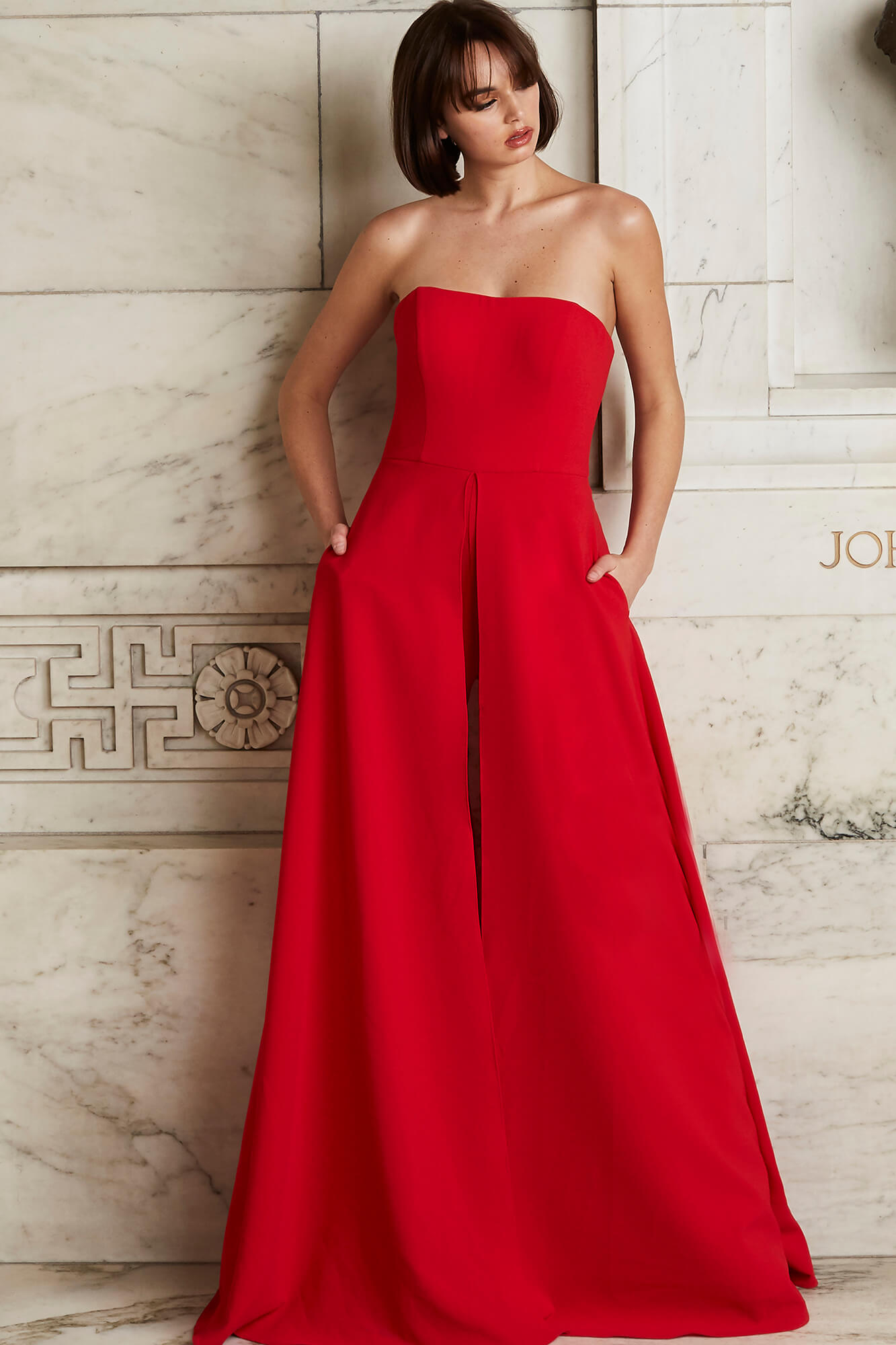 Model wearing Jovani 03529 red jumpsuit, full front view, highlighting the chic strapless fit and wide-leg structure.