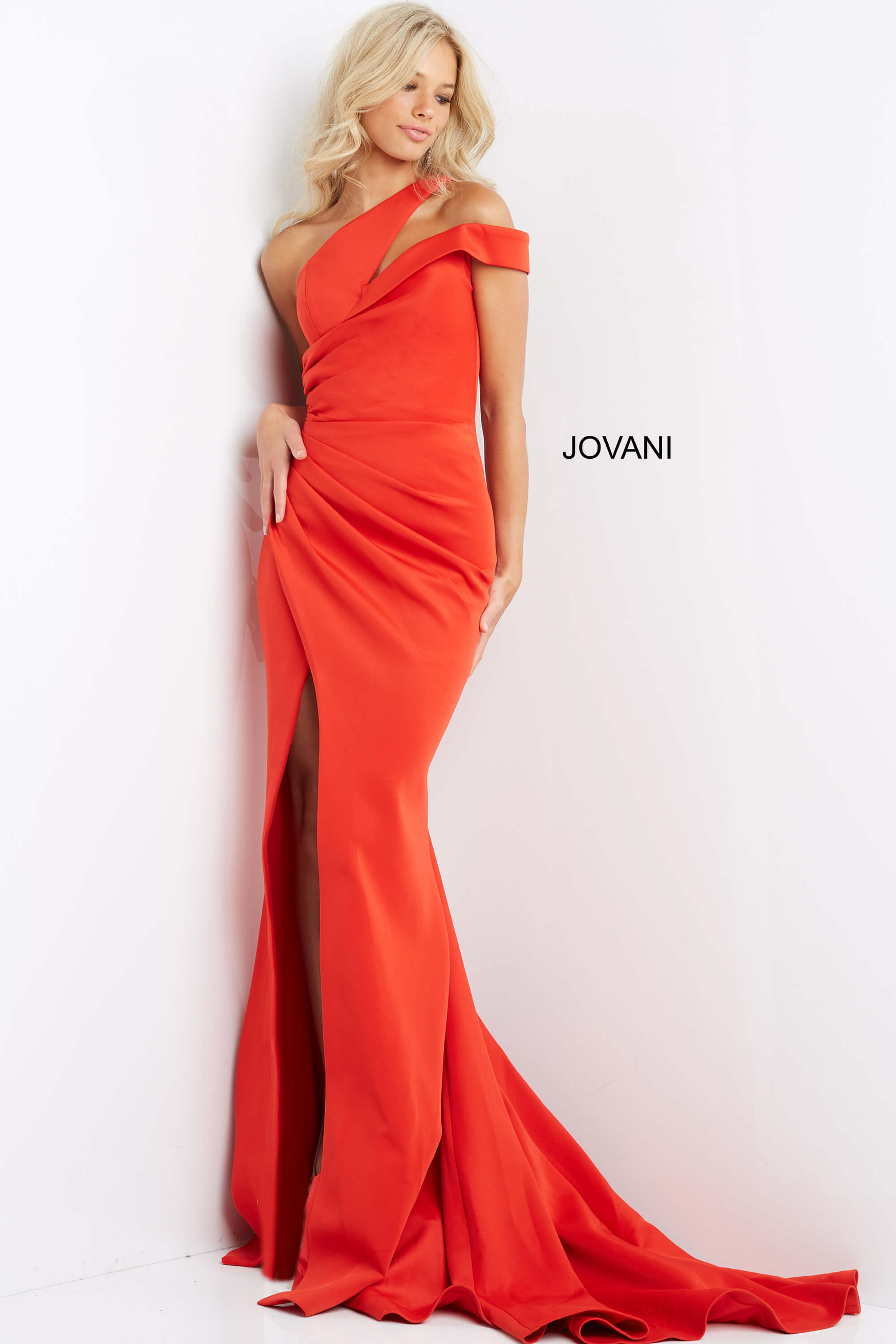 Model in Jovani 04222 orange dress with one-shoulder design and slit.