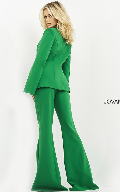 Model wearing Jovani 06922 emerald green jumpsuit with cape sleeves, back view.
