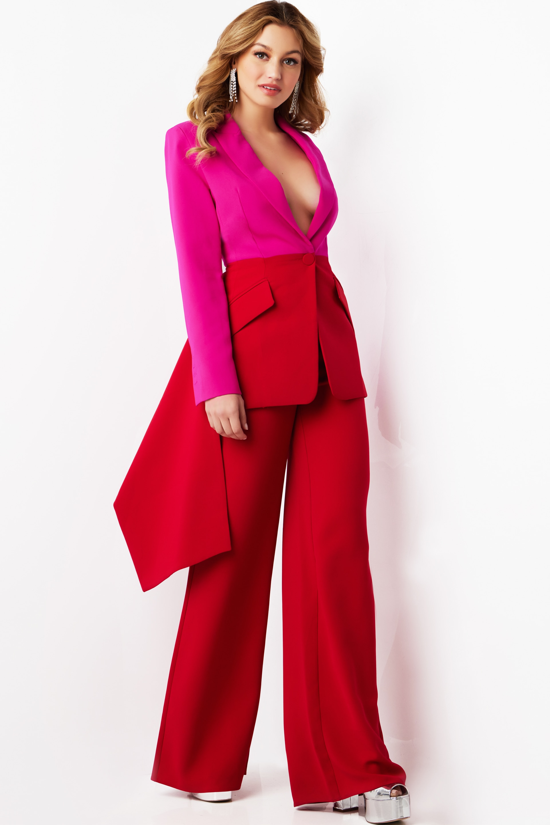 Model wearing Jovani 07093 fuchsia blazer and red trousers with side drape front view.