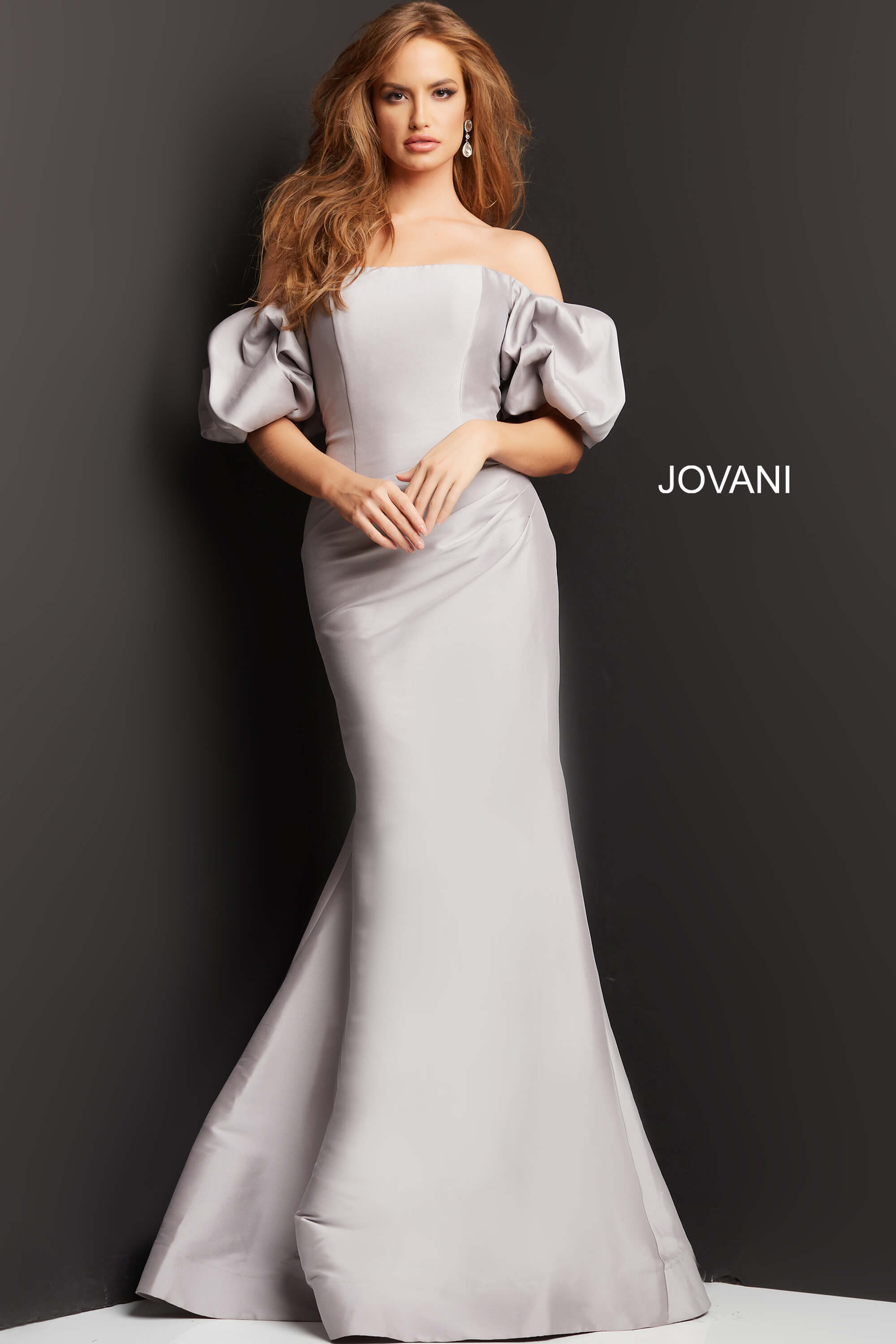Model wearing Jovani 08361 taupe mermaid gown with off-shoulder puff sleeves.