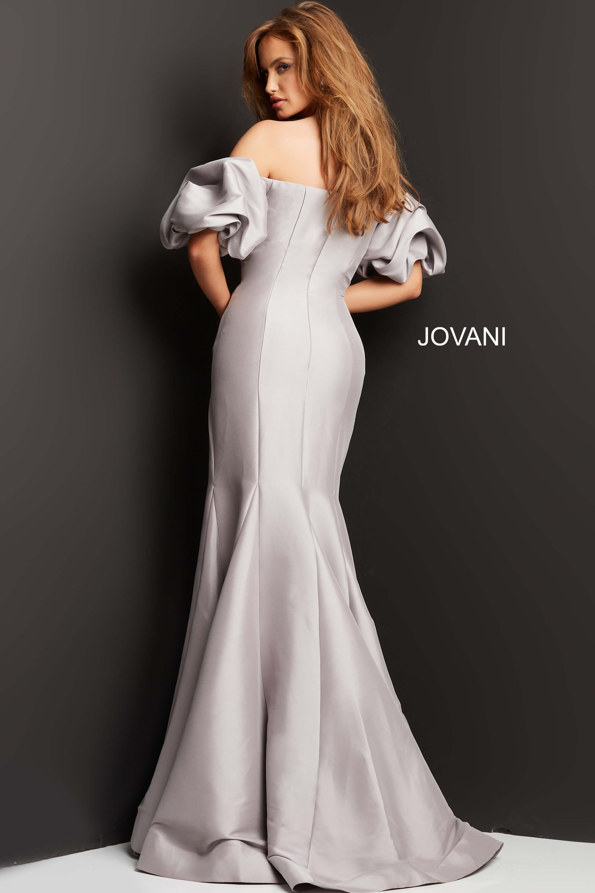 Back view of model in Jovani 08361 taupe mermaid gown with off-shoulder puff sleeves.