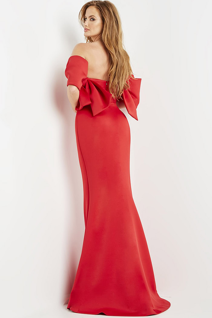 Model wearing Jovani 09064 red dress showing the back and large bow detail.