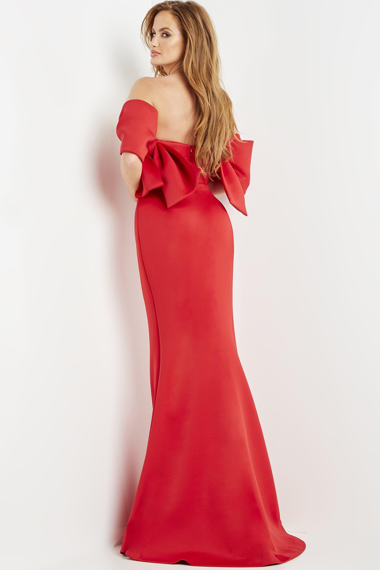 Model wearing Jovani 09064 red dress showing the back and large bow detail.