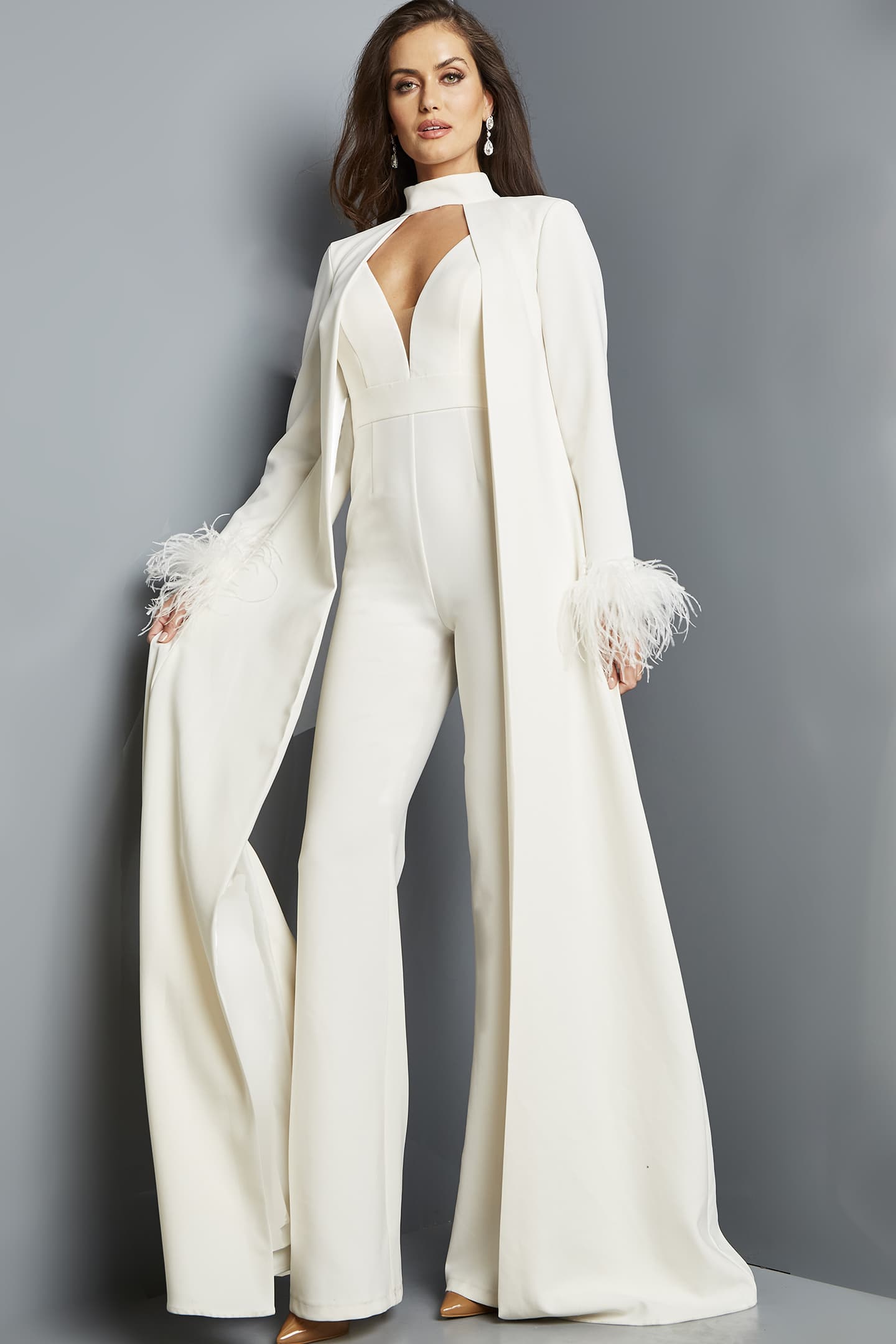 Model wearing Jovani 09479 ivory jumpsuit with coat and feathered cuffs from the front