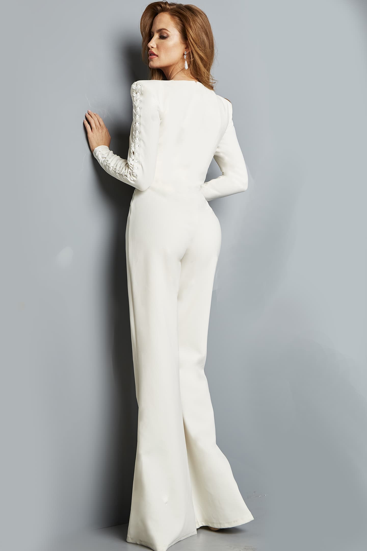 model showcasing back view of Jovani 09588 white jumpsuit with lace-up sleeve detail