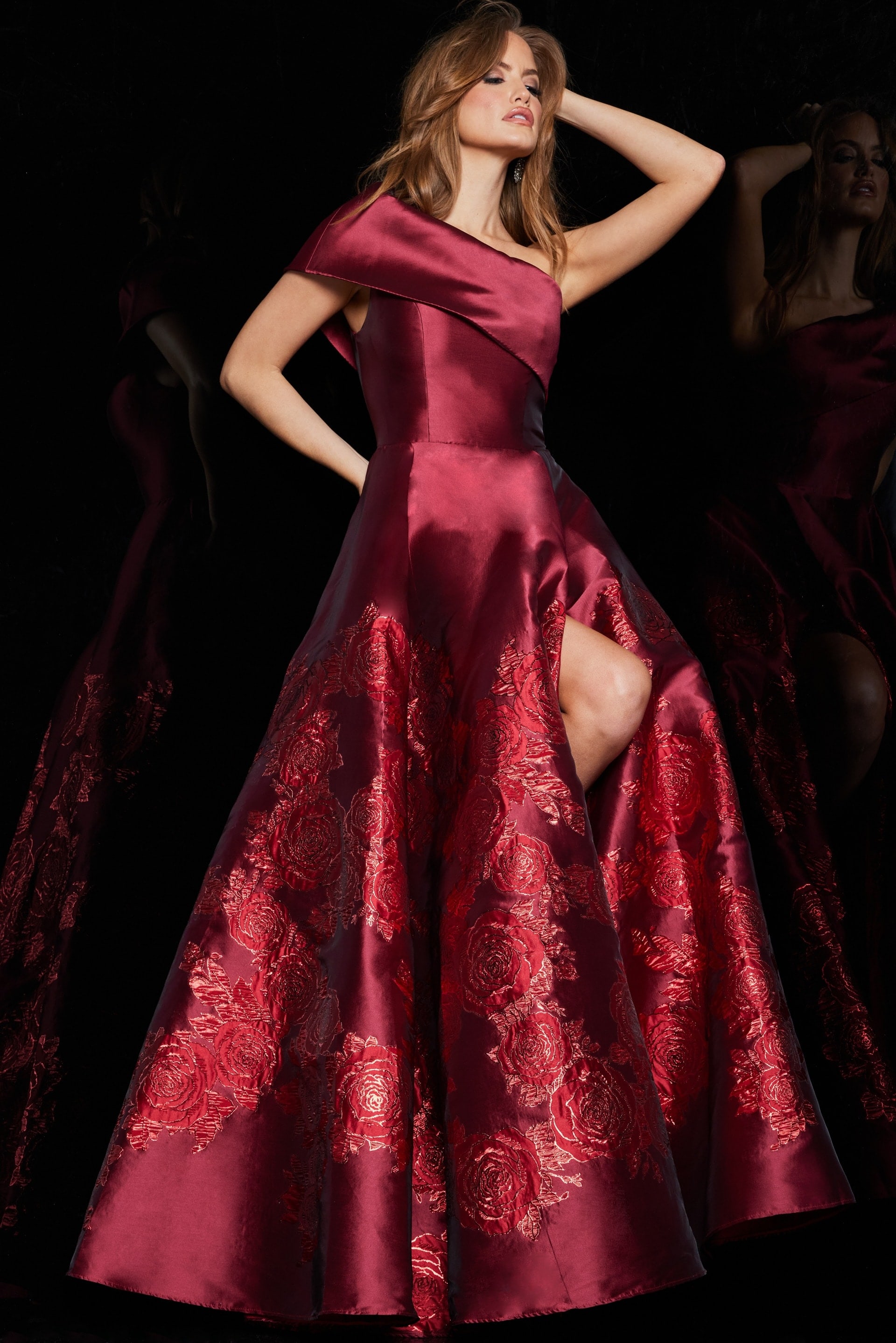 Model in Jovani 09610 red dress with asymmetric neckline and high slit.