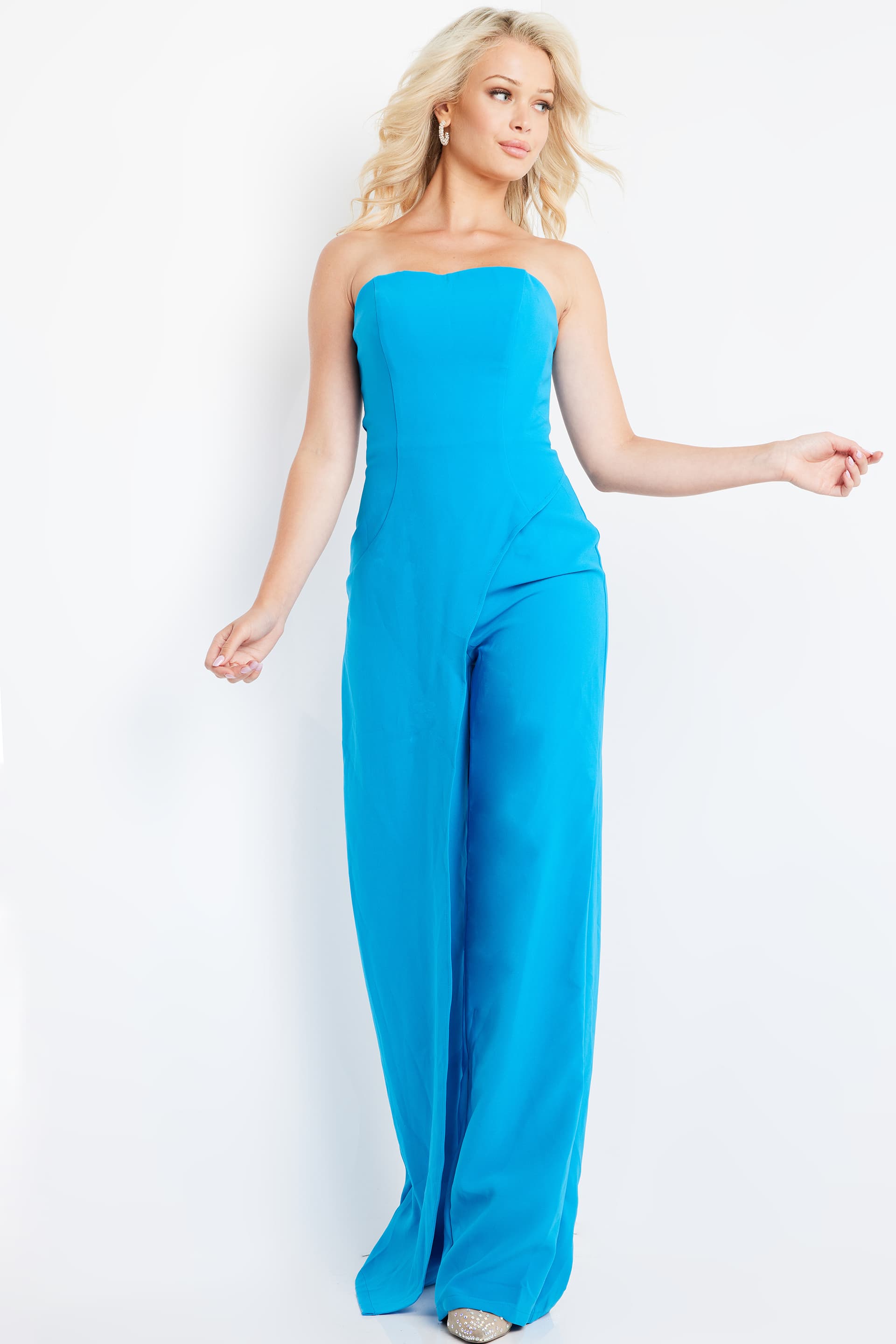Model wearing Jovani 23082 blue strapless jumpsuit in motion.