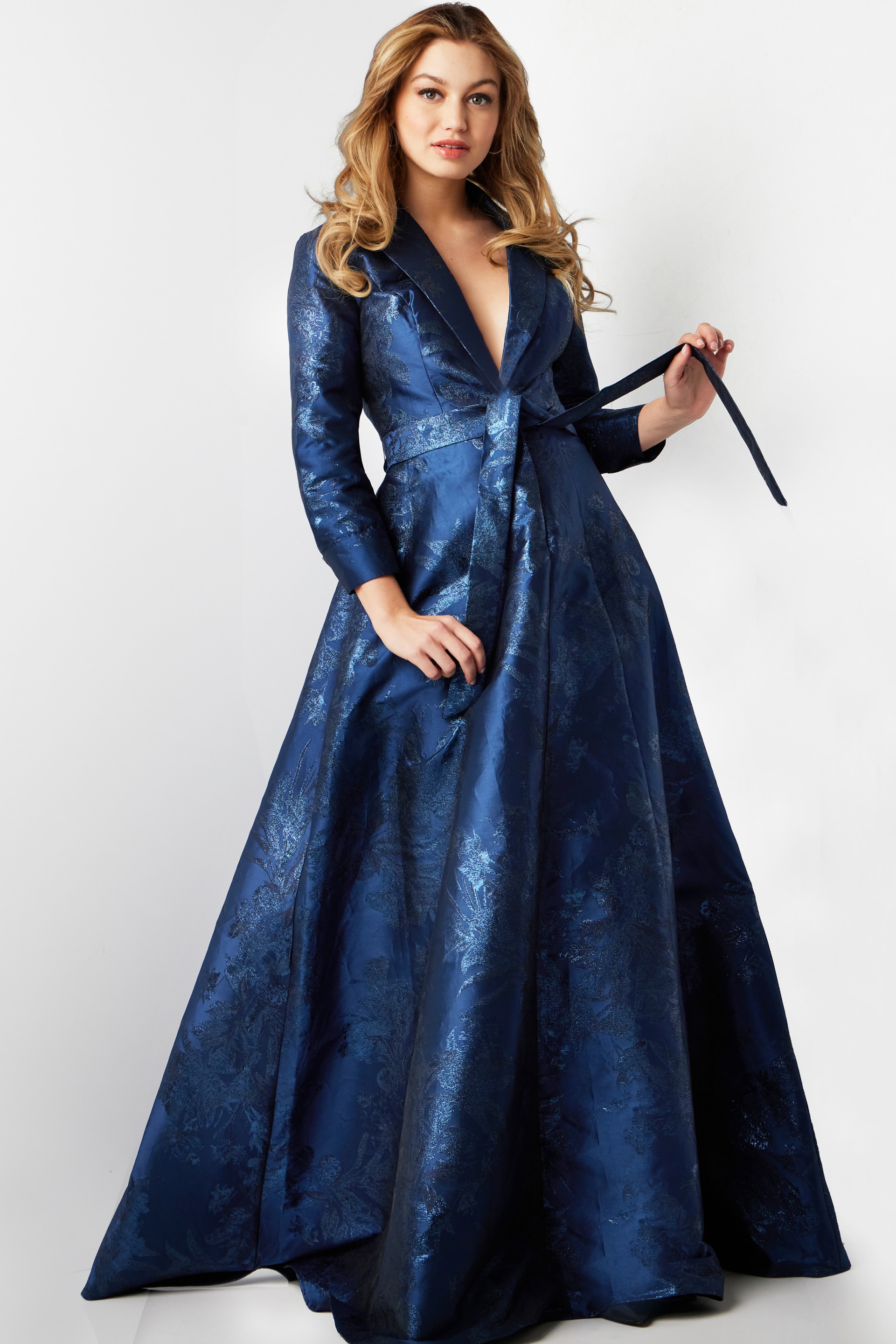 Model wearing Jovani 23178 navy floral brocade dress holding sash