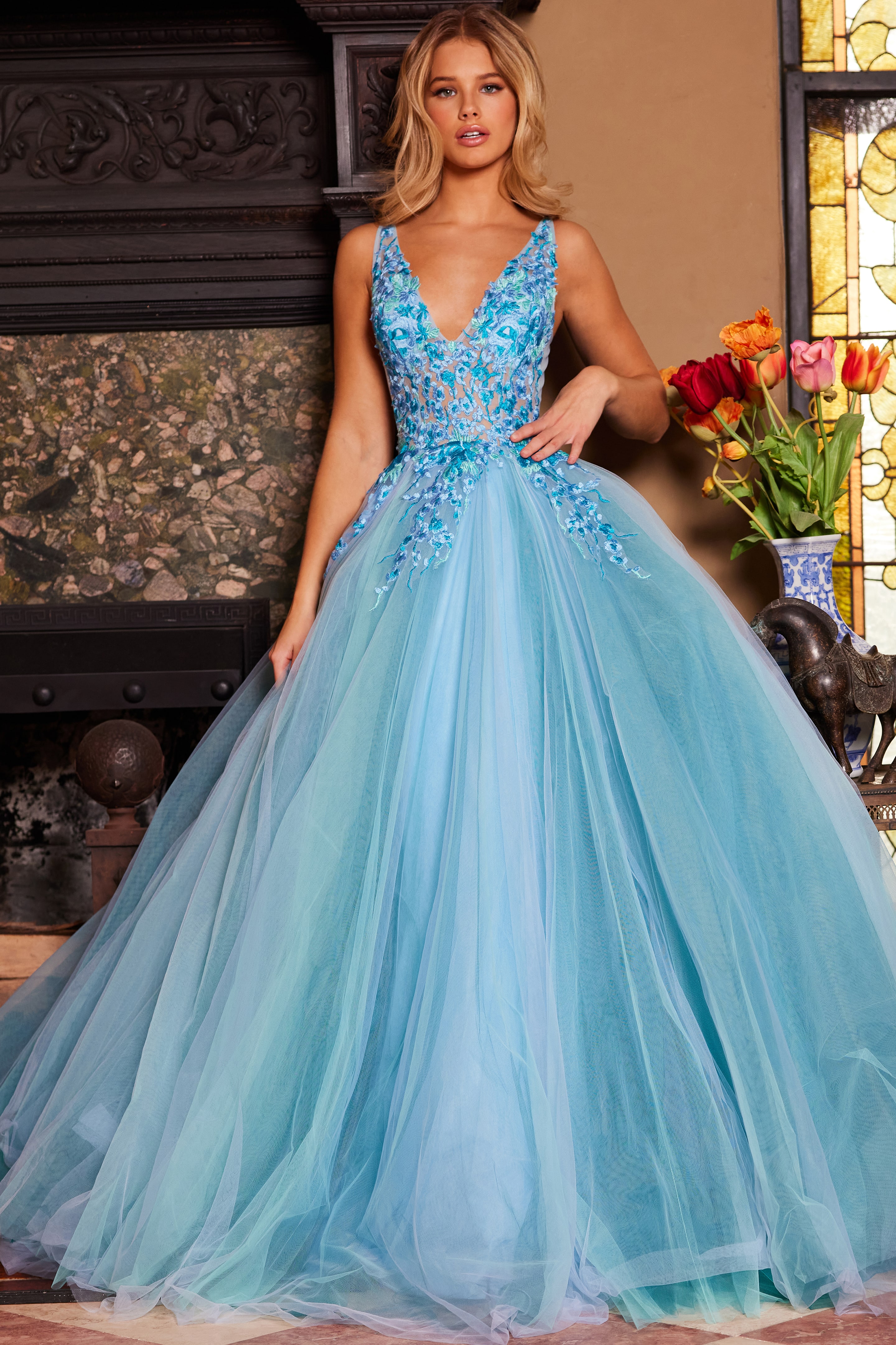 Model wearing Jovani 23577 blue gown with deep V-neckline front view.