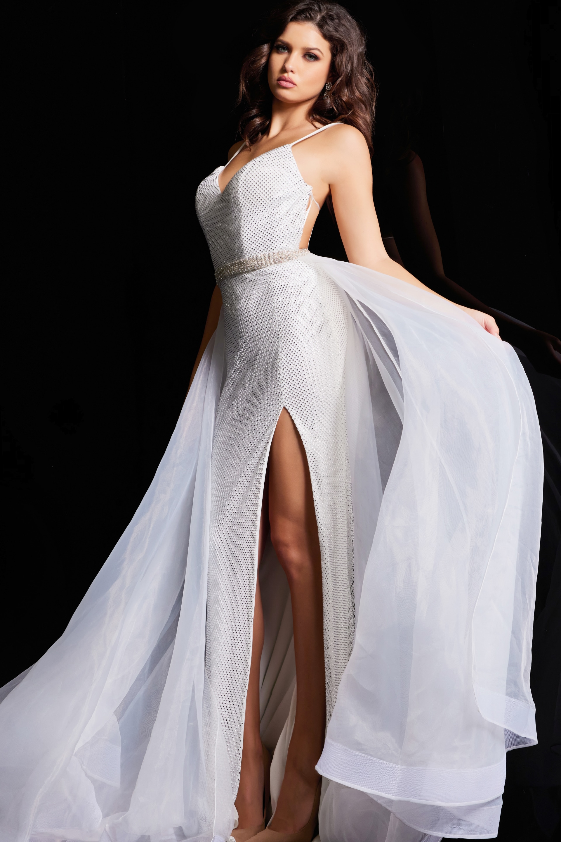 Model showcasing Jovani 25990 white gown with intricate beadwork and high slit.