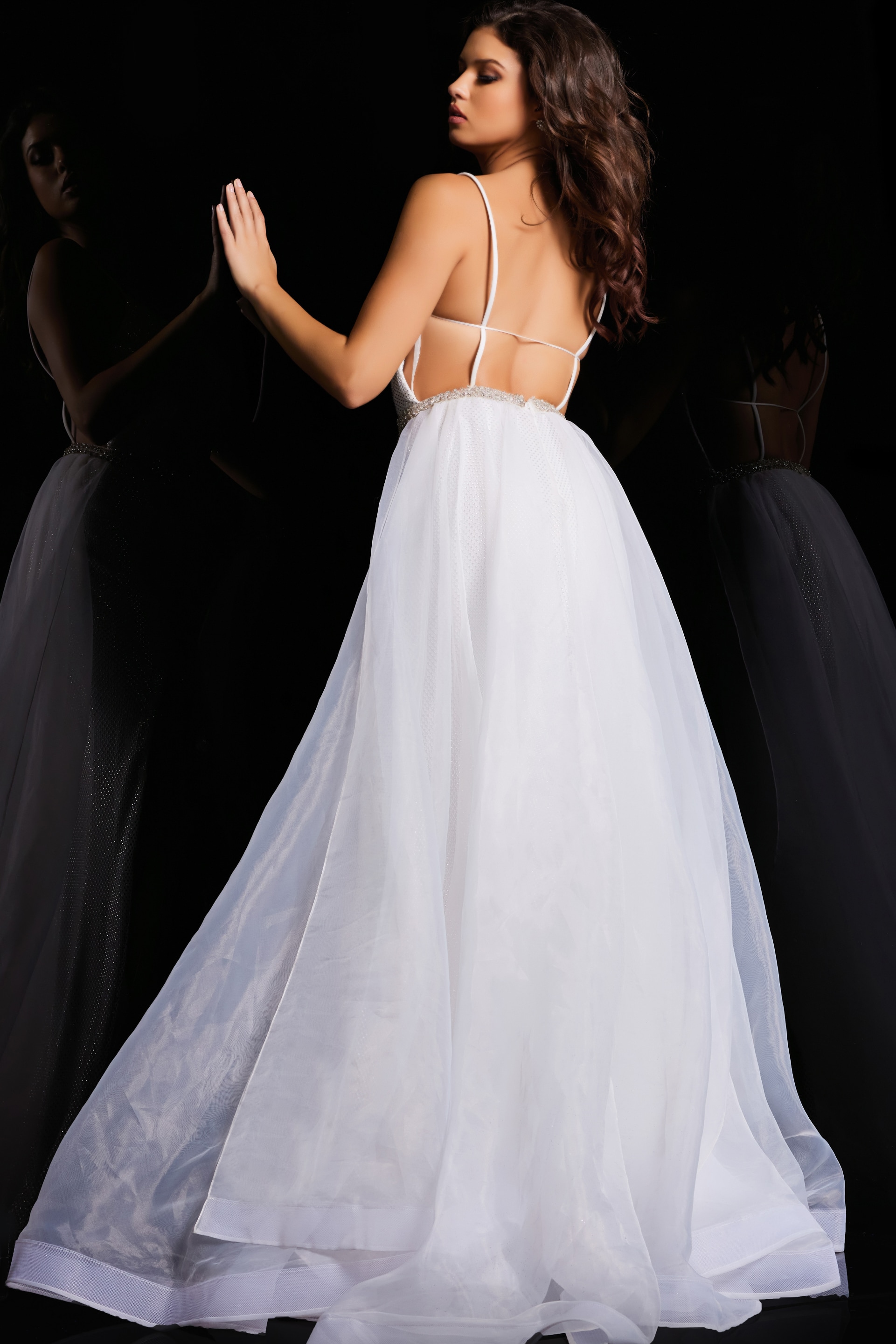 Back view of model wearing Jovani 25990 white gown with open back design.