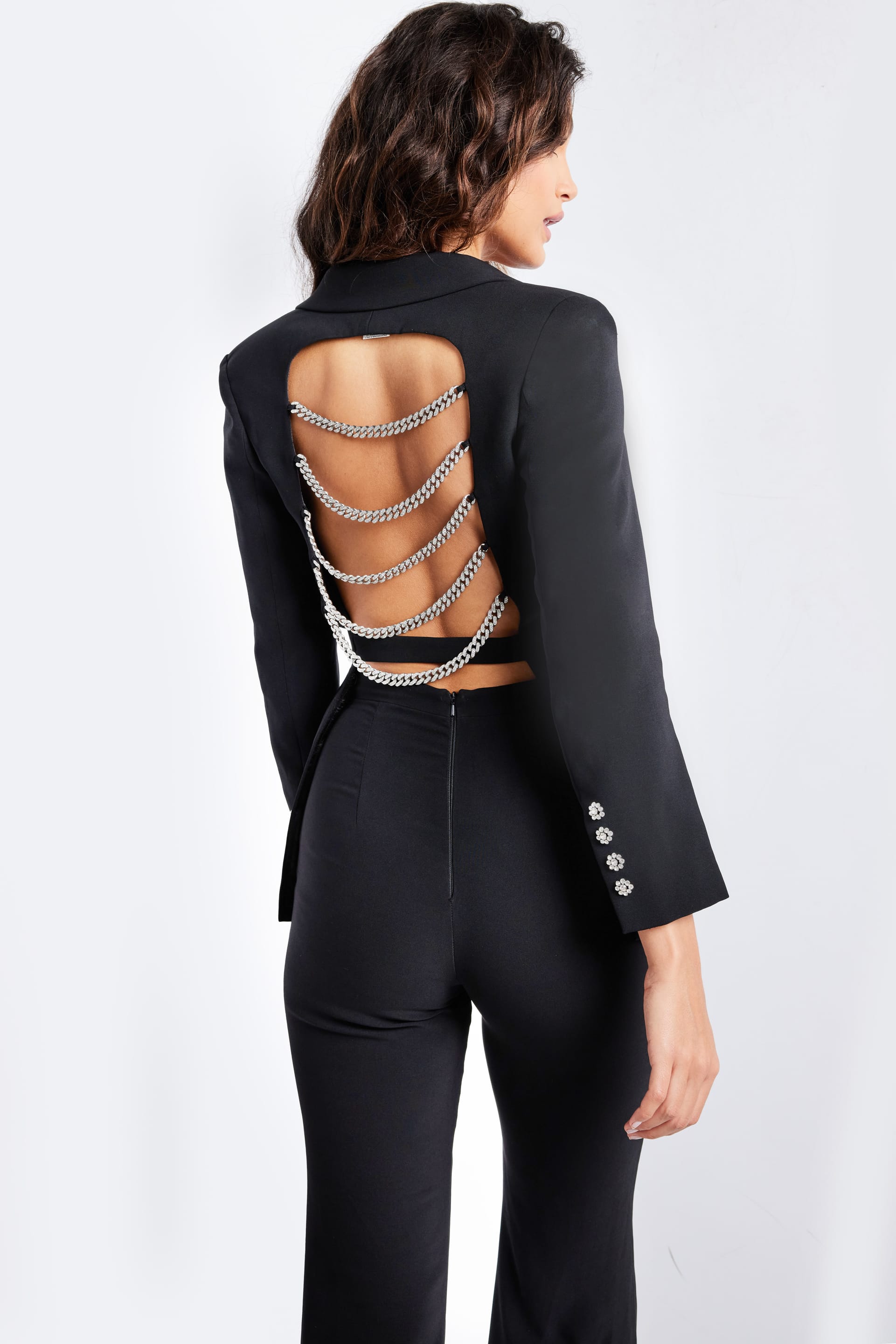 Model in Jovani 26144 black ensemble with striking open-back chain embellishment.