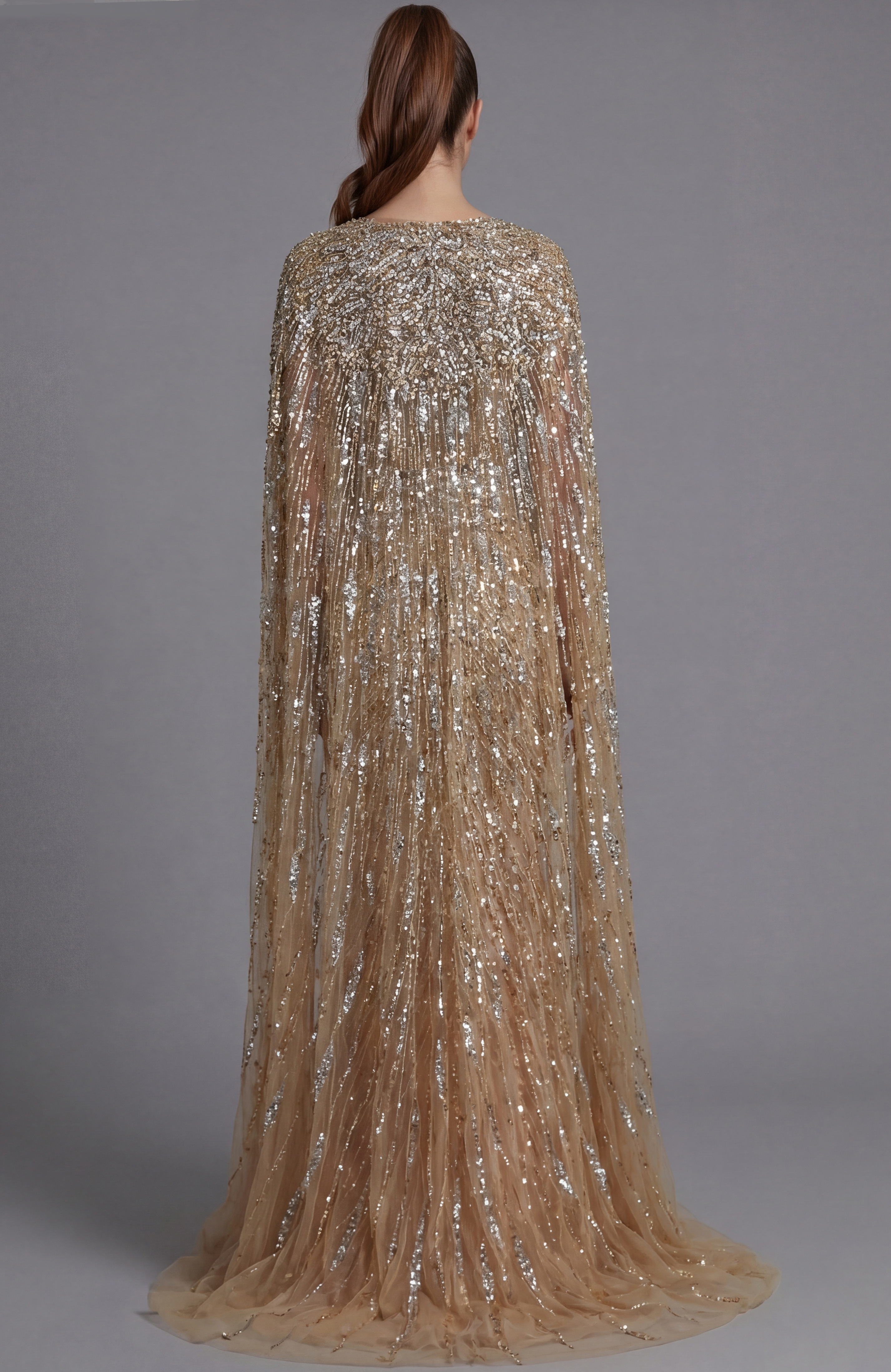 Back view of a beaded gown with flowing cape sleeves and fitted column silhouette