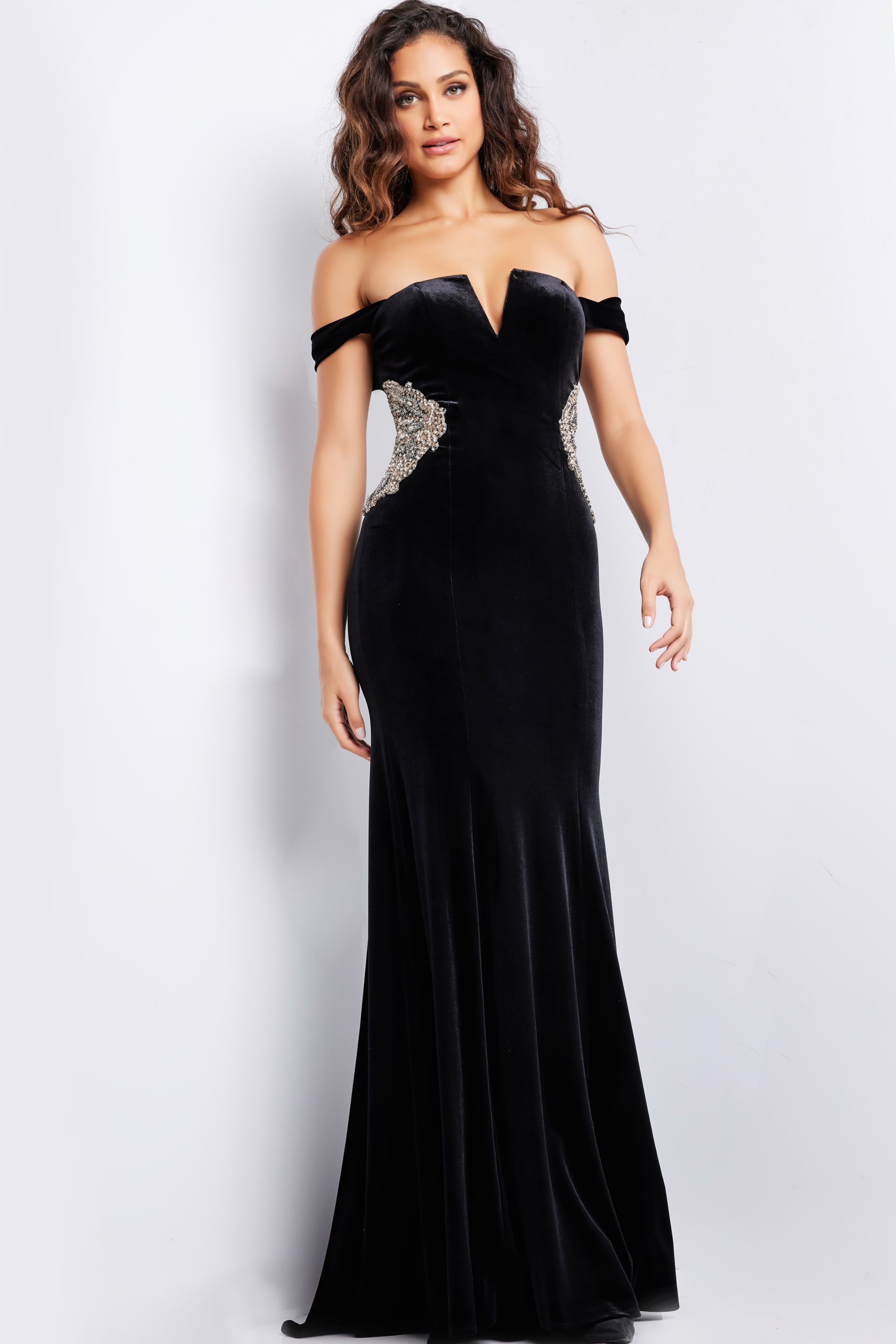 Model wearing Jovani 36733 black off-the-shoulder gown with side embellishments, front view.