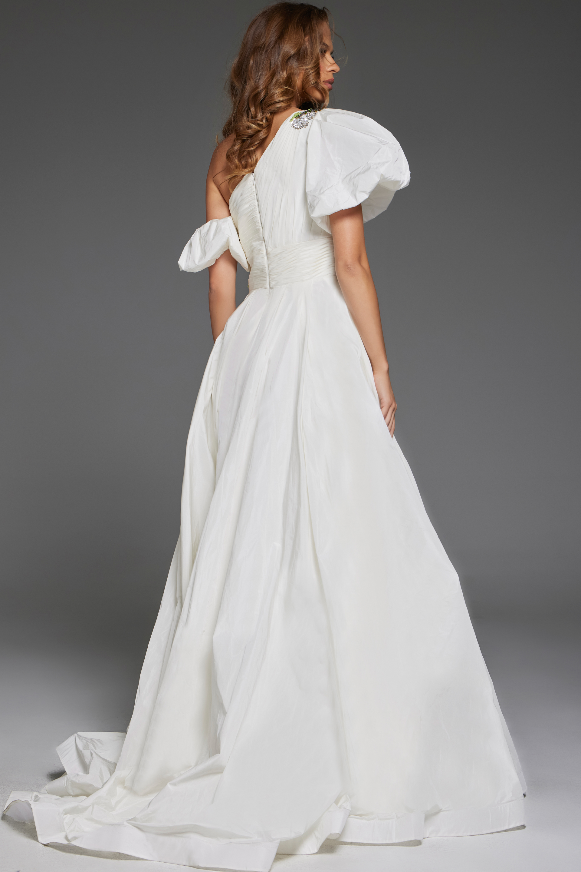 model wearing Jovani 36872 white one-shoulder gown with floral embellishments and high slit