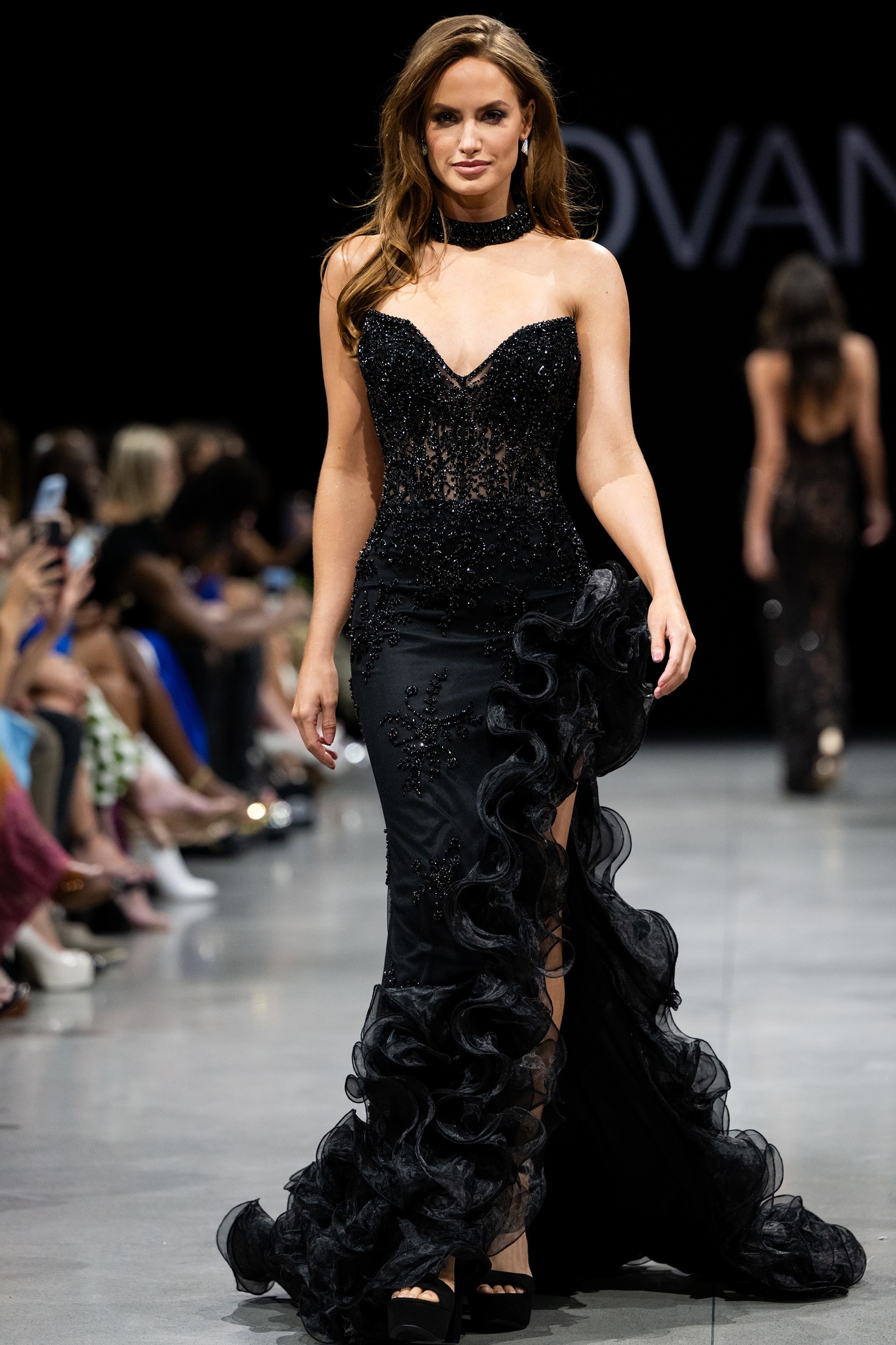 Model wearing Jovani 37036 black dress with sweetheart neckline and ruffled details.