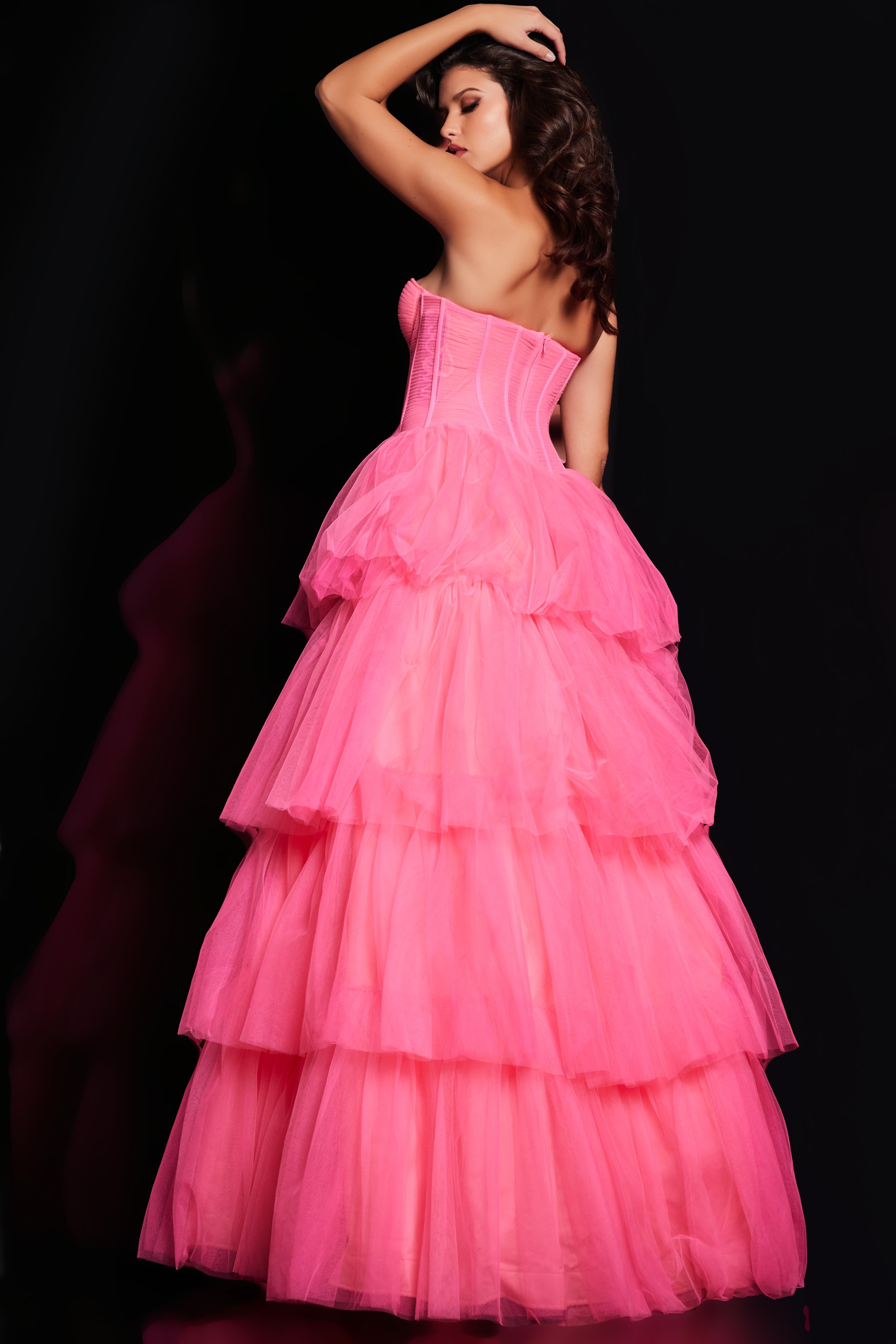 Model wearing Jovani 37062 pink gown with tiered skirt, back view.
