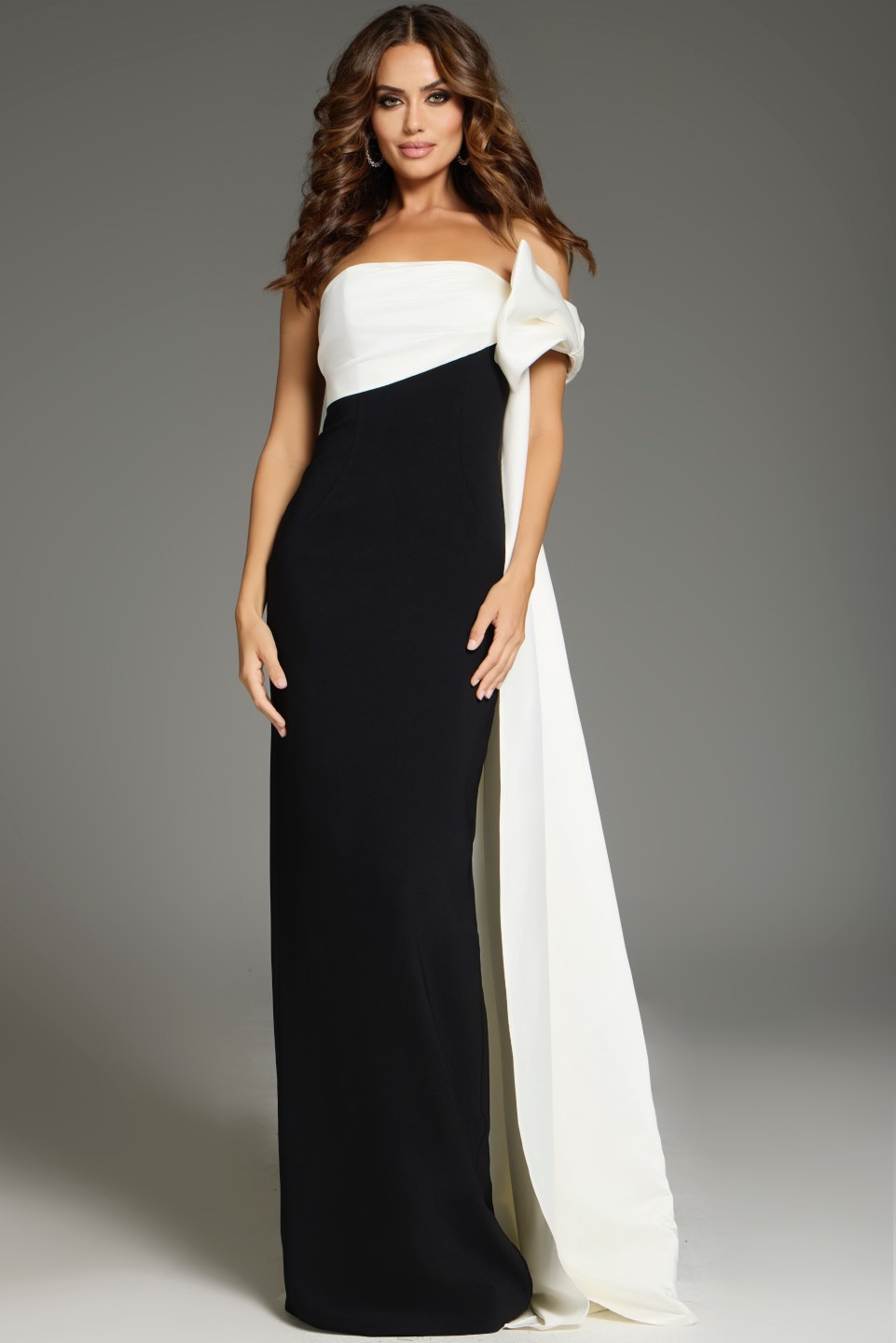Model wearing Jovani 38864 chic black and white gown with unique shoulder drape