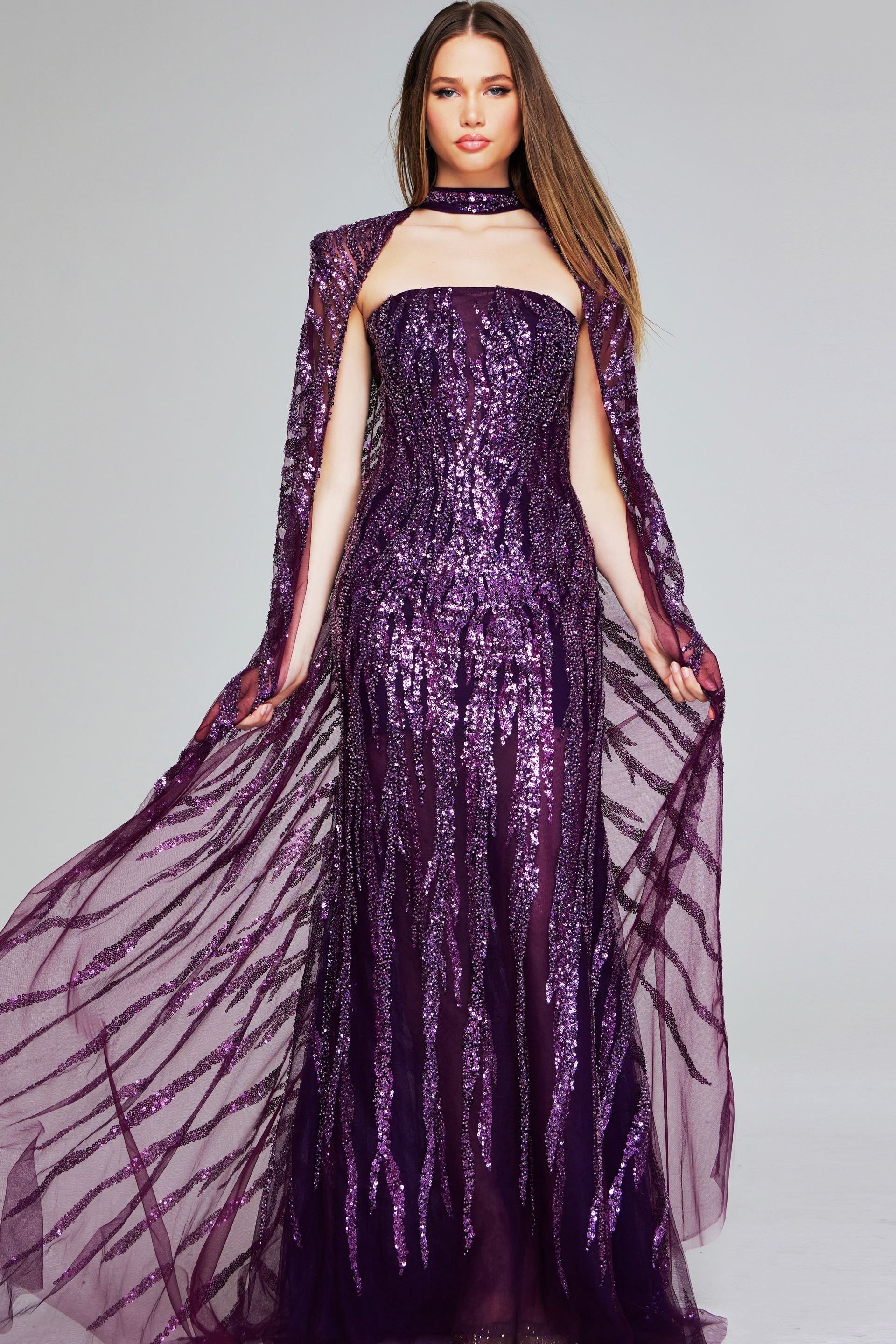 Model wearing Jovani 39046 purple gown with sequins and cape sleeves, front view.