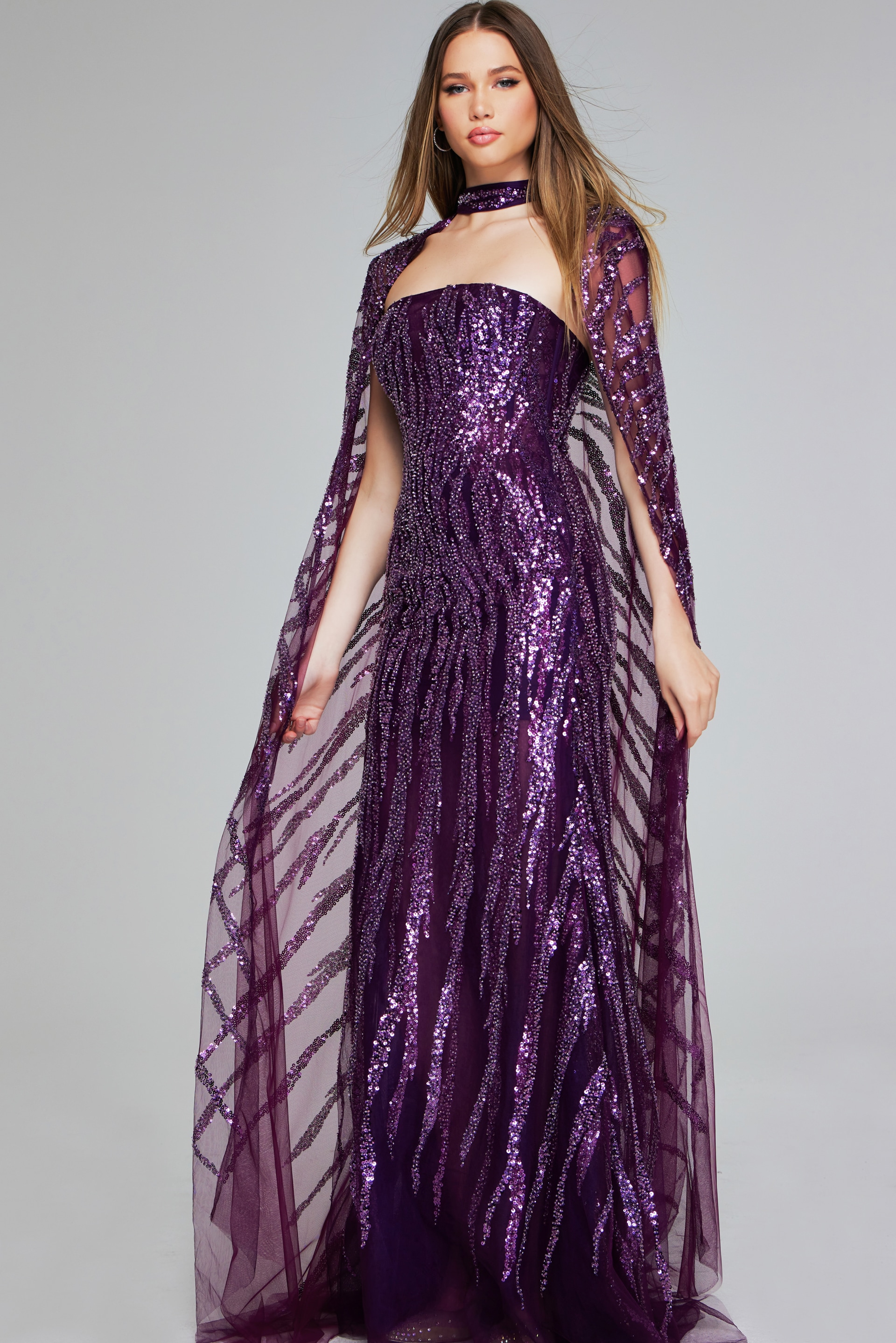Model in Jovani 39046 purple gown, showcasing sequins and cape sleeves from the front.