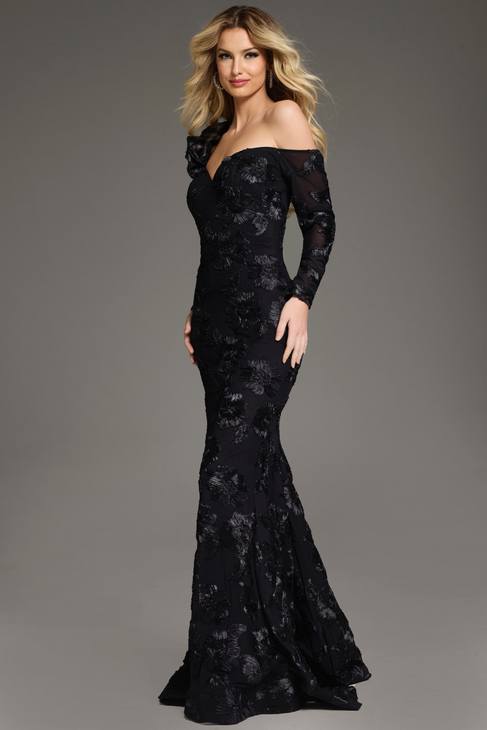 Model presenting Jovani 39266 black gown with elegant floral accents and long single sleeve.
