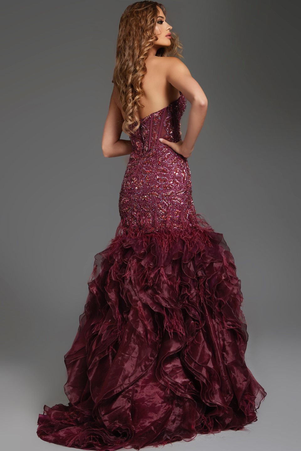 Side-back view of model in Jovani 39712 burgundy dress highlighting silhouette.