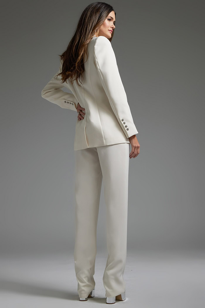 Model wearing Jovani 39726 ivory pant suit with silver embellishments, back view.