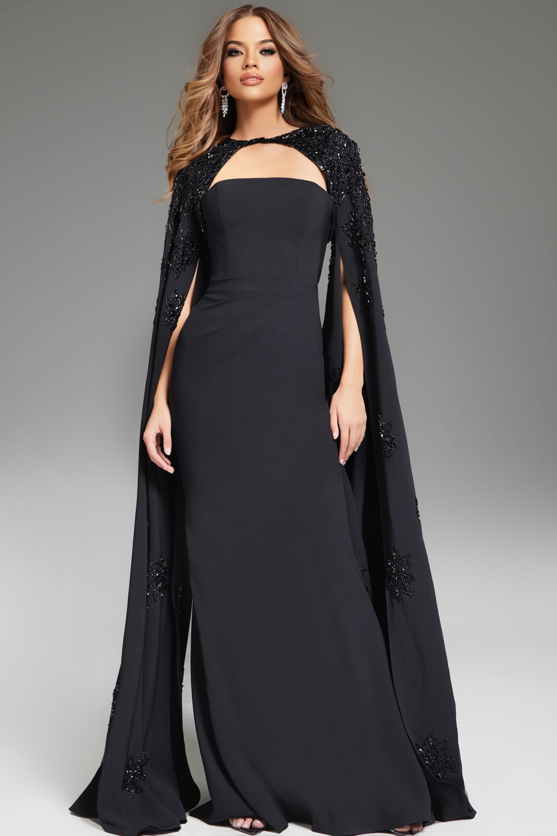 model wearing Jovani 39957 floor-length black gown with strapless neckline and embellished cape