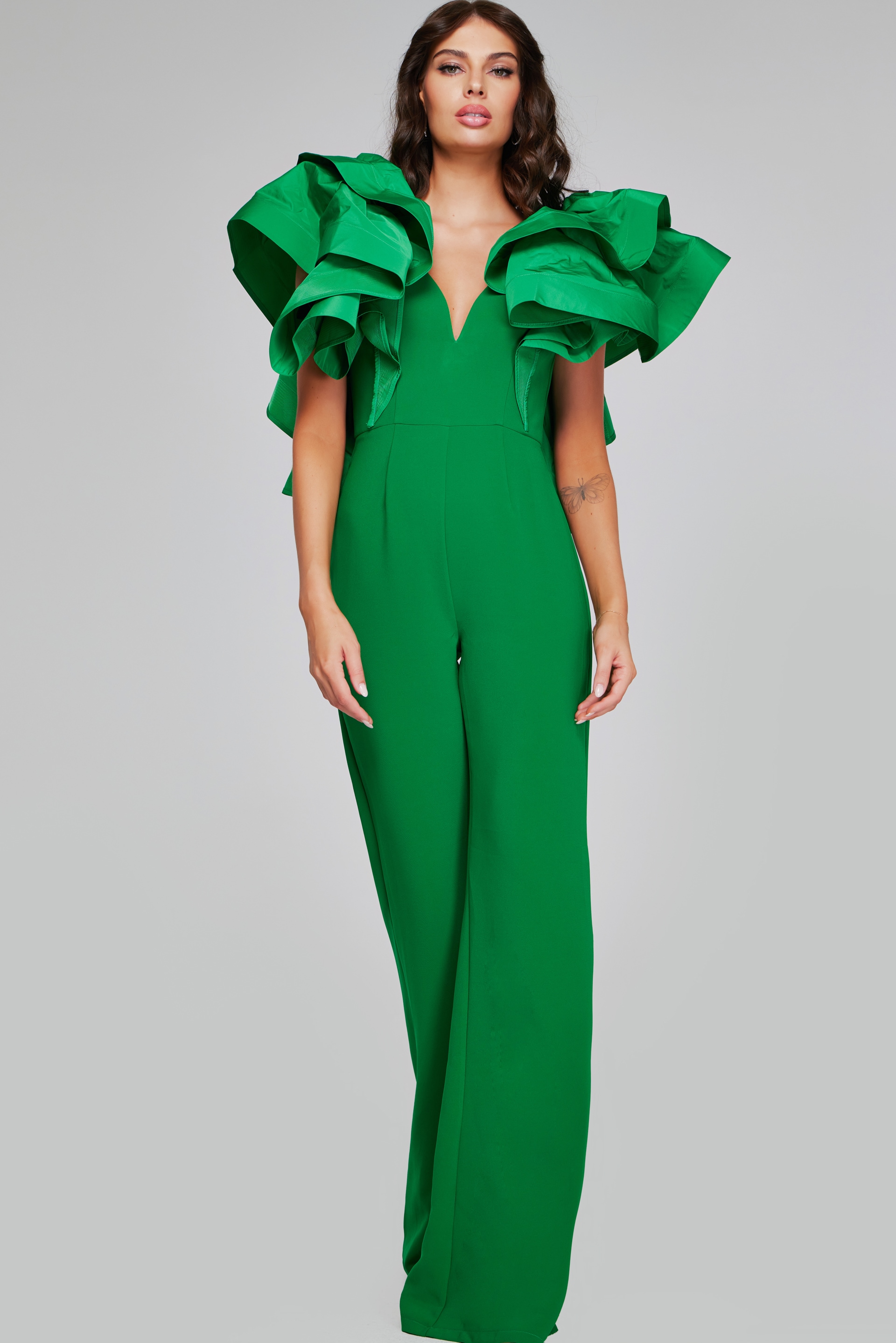 Model wearing Jovani 40291 emerald green jumpsuit with detailed view of the ruffled sleeves.