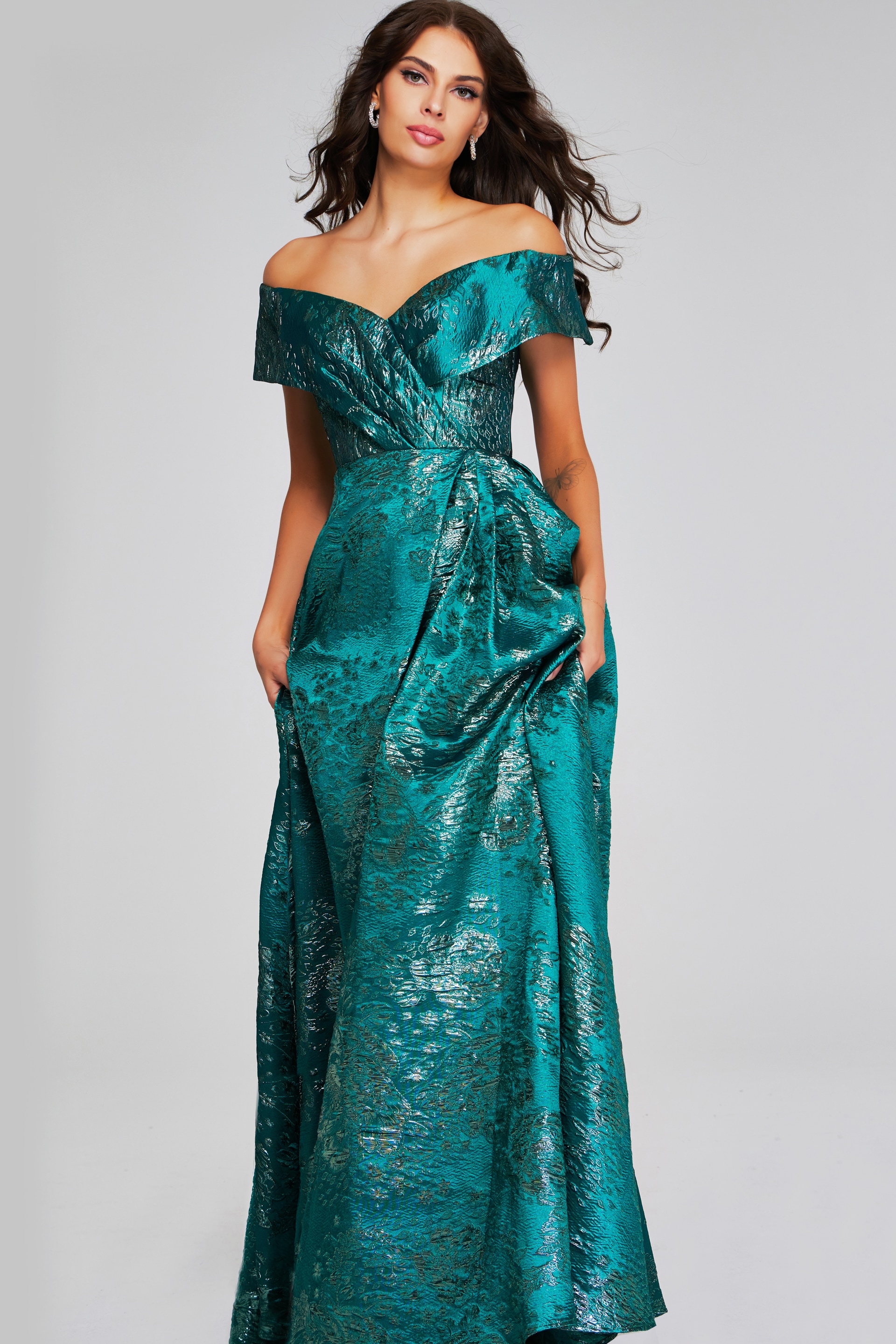 Model wearing Jovani 40296 green dress, off-the-shoulder, front view, holding skirt.