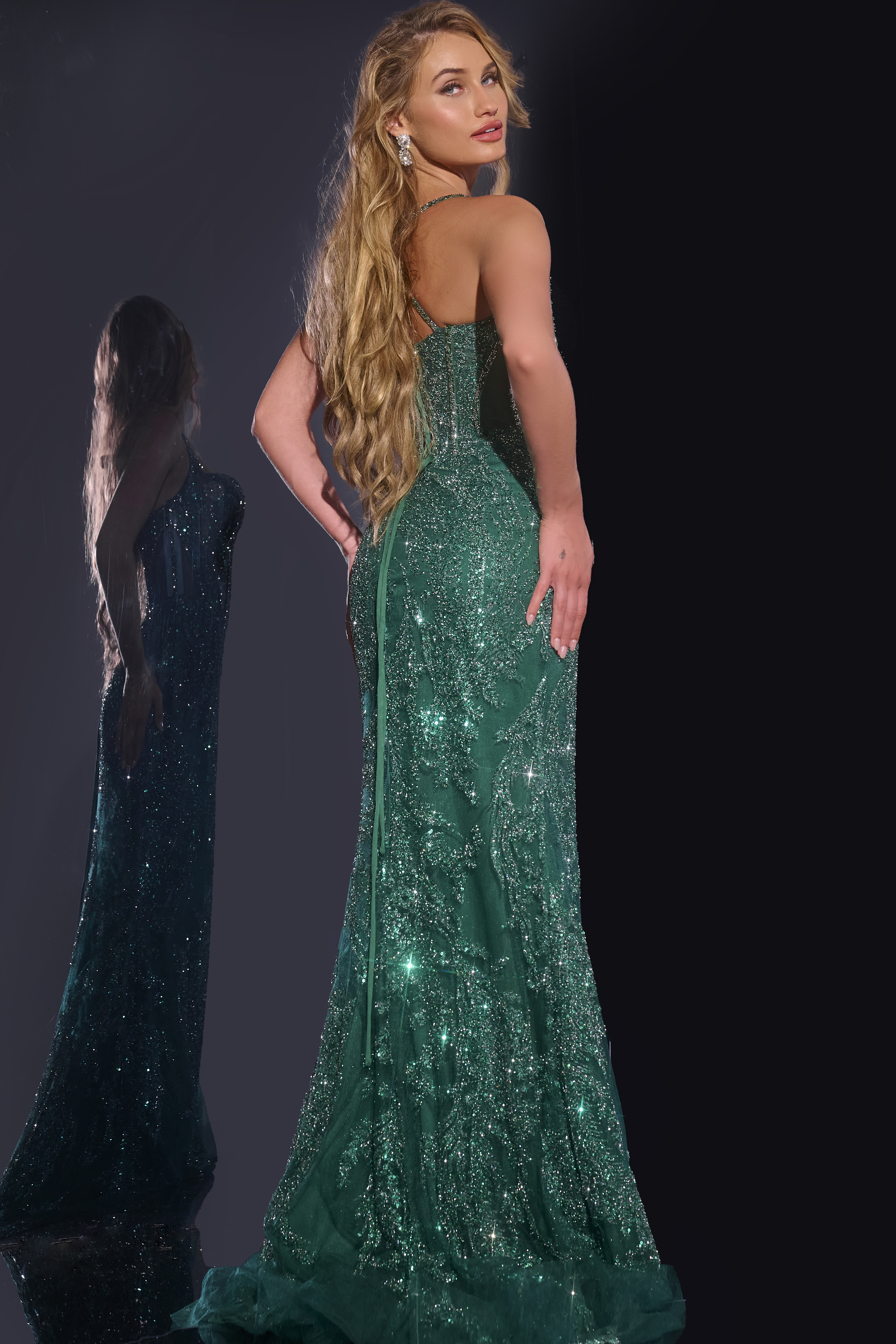 Model wearing Jovani 40470 green mermaid gown with embellishments, back view.