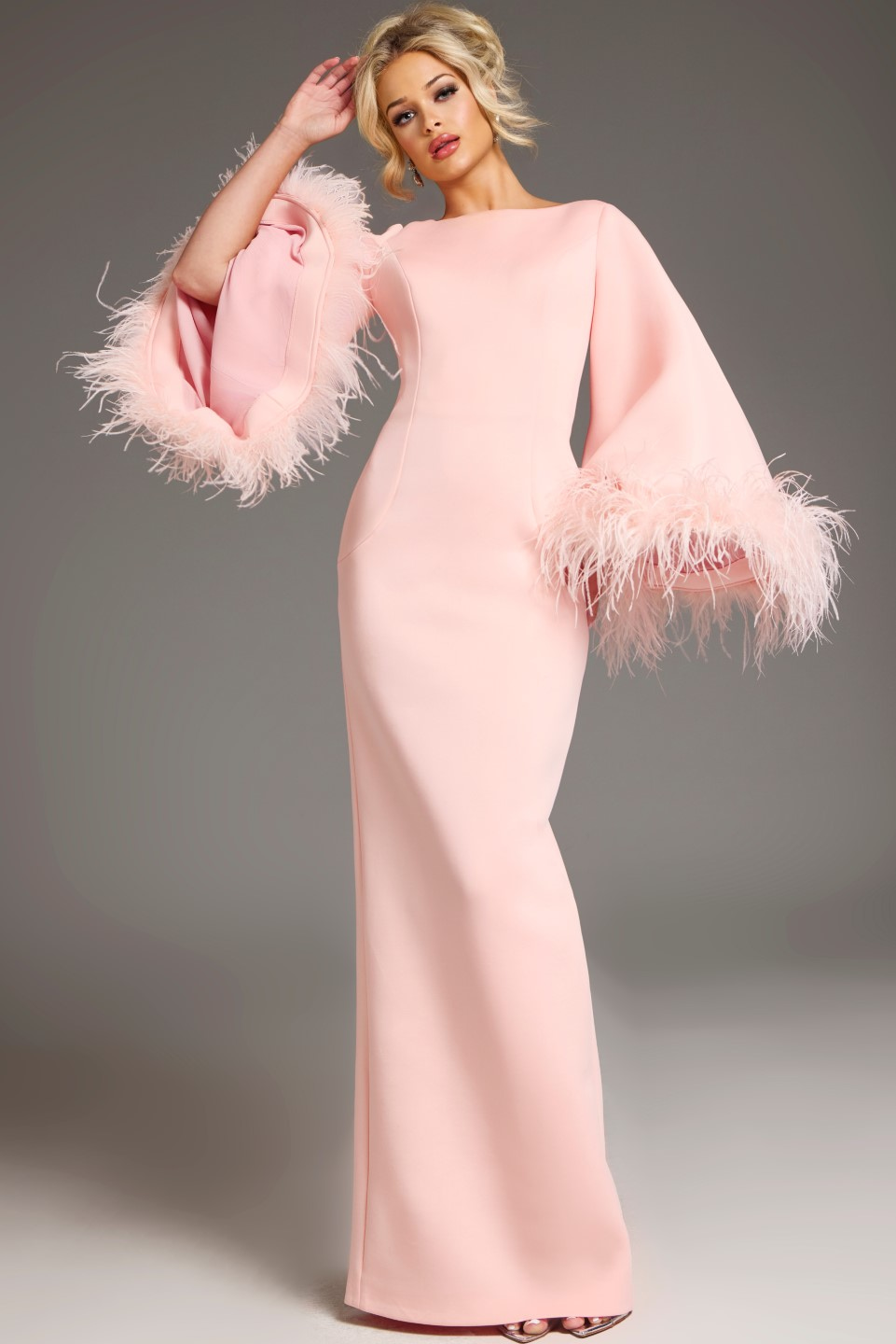 Model in Jovani 41077 blush gown showcasing the full view with feather-adorned bell sleeves.
