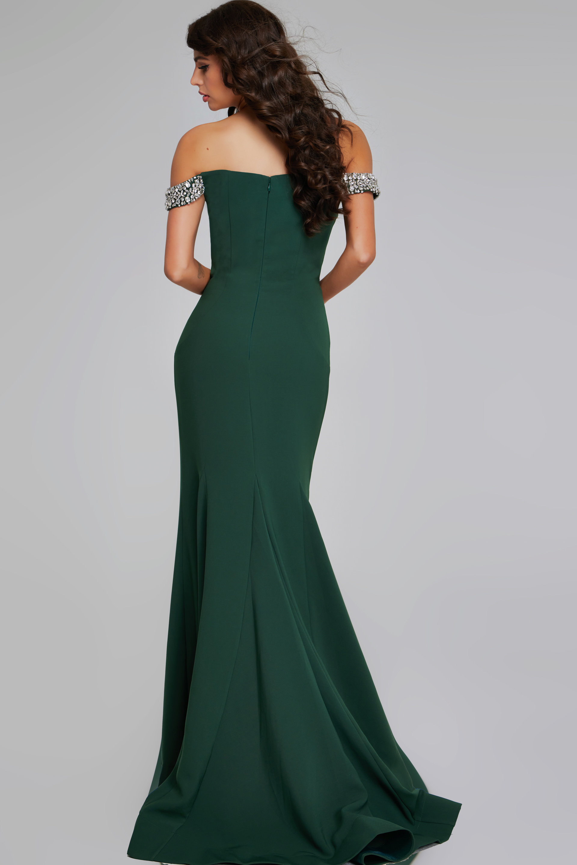 Model showing the back of Jovani 42394 green gown with a subtle flared skirt.