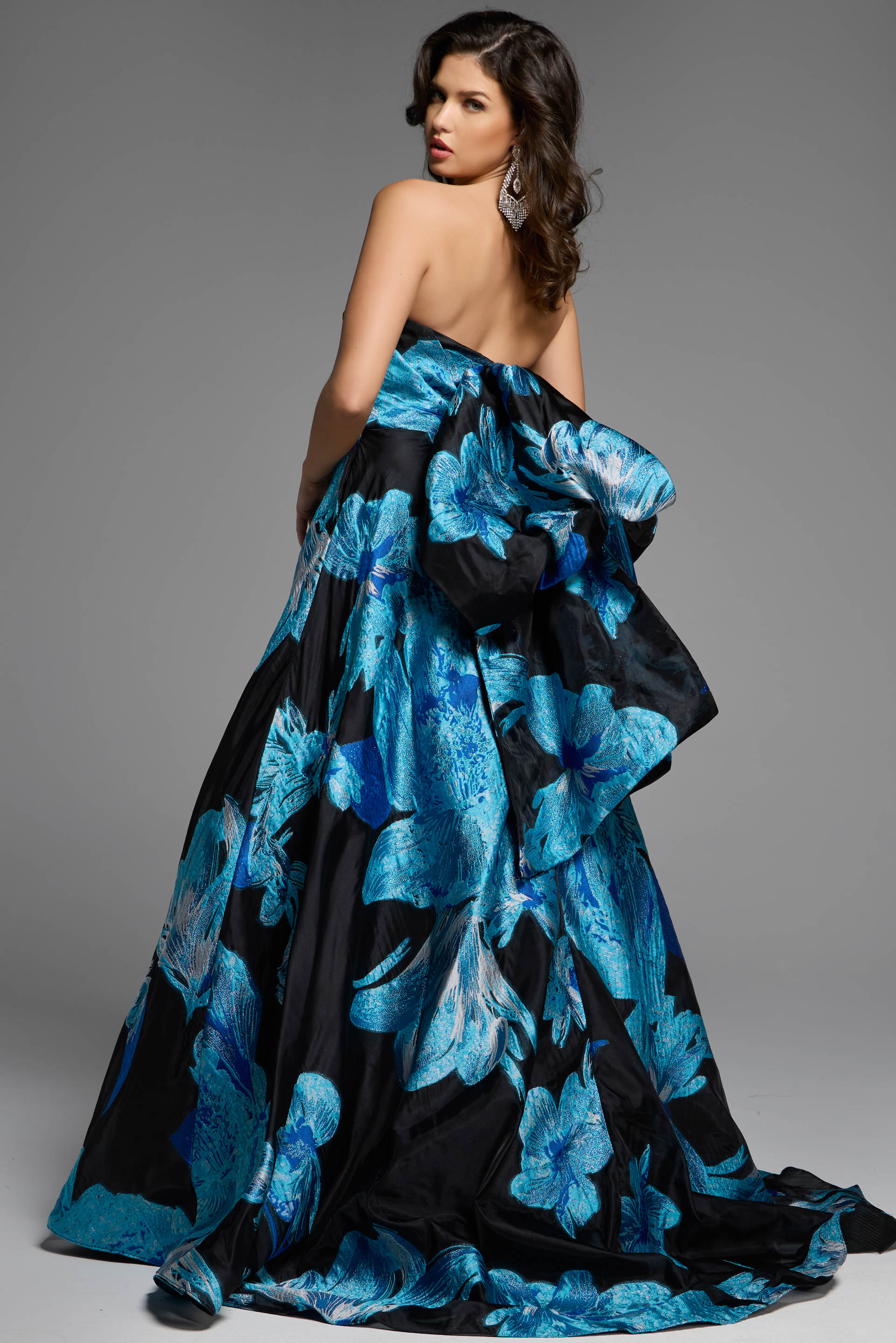 Back view of a strapless black gown showcasing a statement bow and floral design.