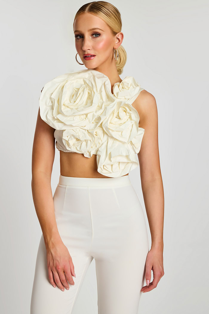 Front view of off-white crop top with oversized sculpted floral design and high-waisted pants