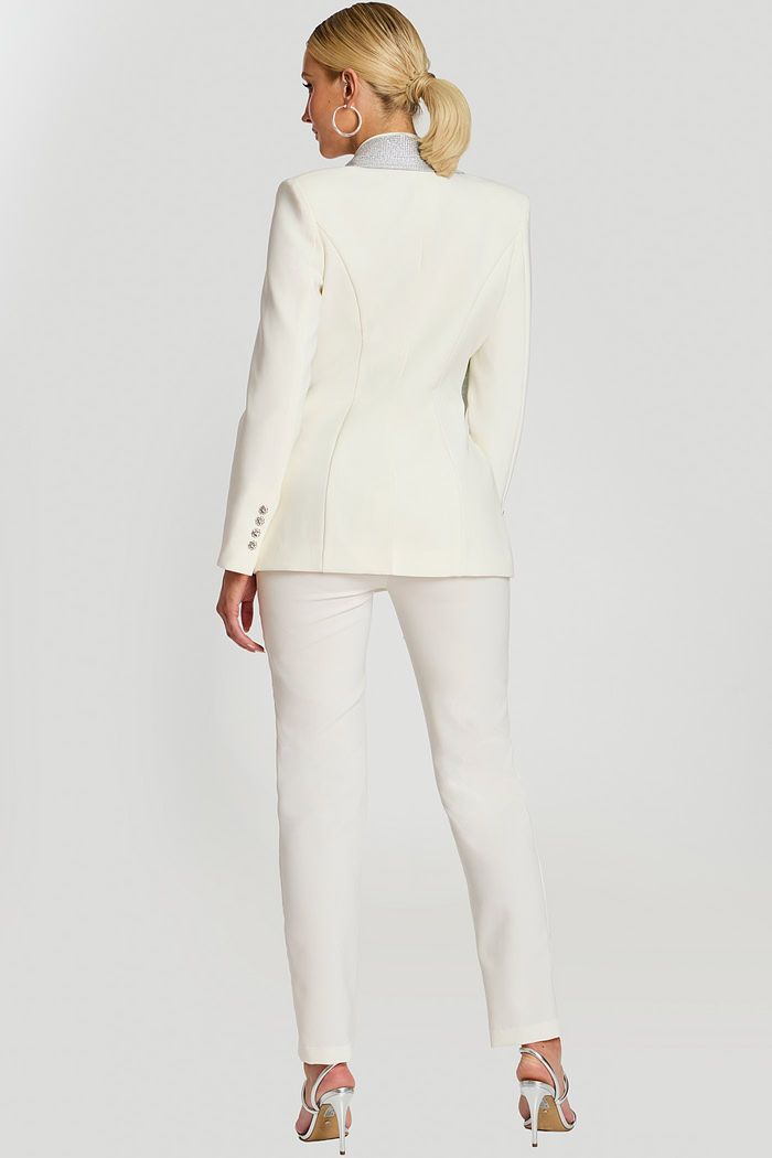 Back view of fitted white suit with structured seams and rhinestone collar