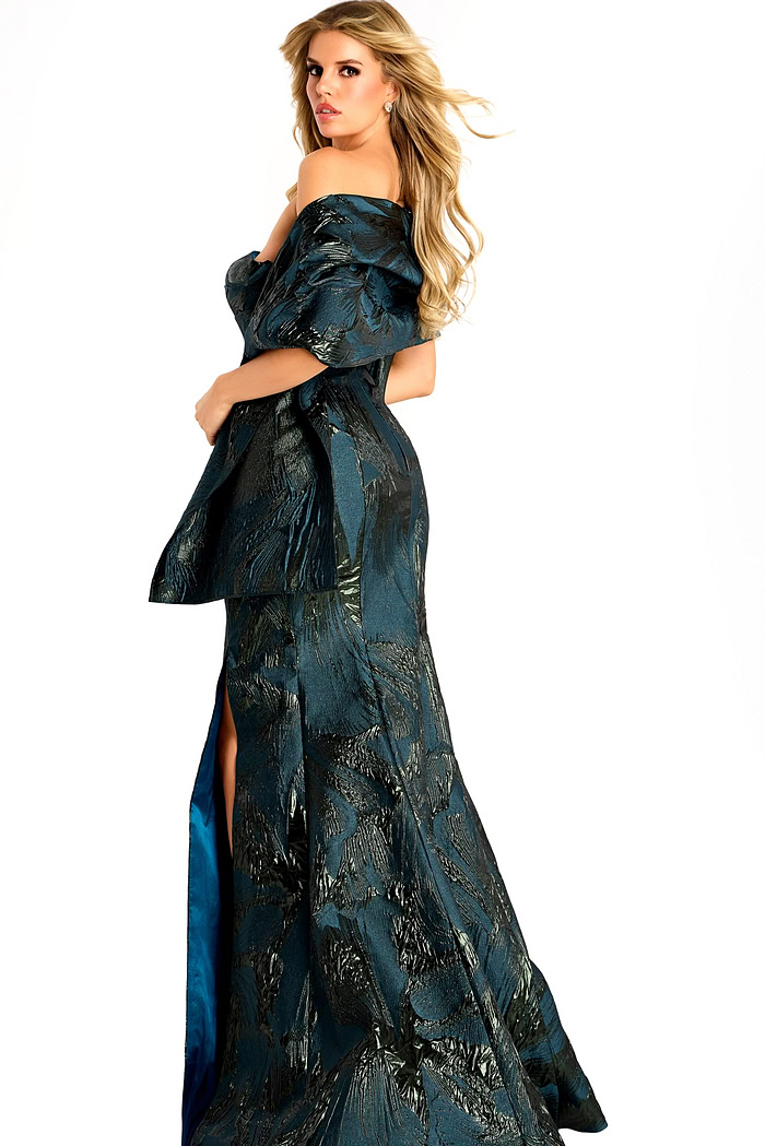 Off-shoulder metallic jacquard gown with structured draped sleeves, fitted bodice, and a floor-length slit skirt.