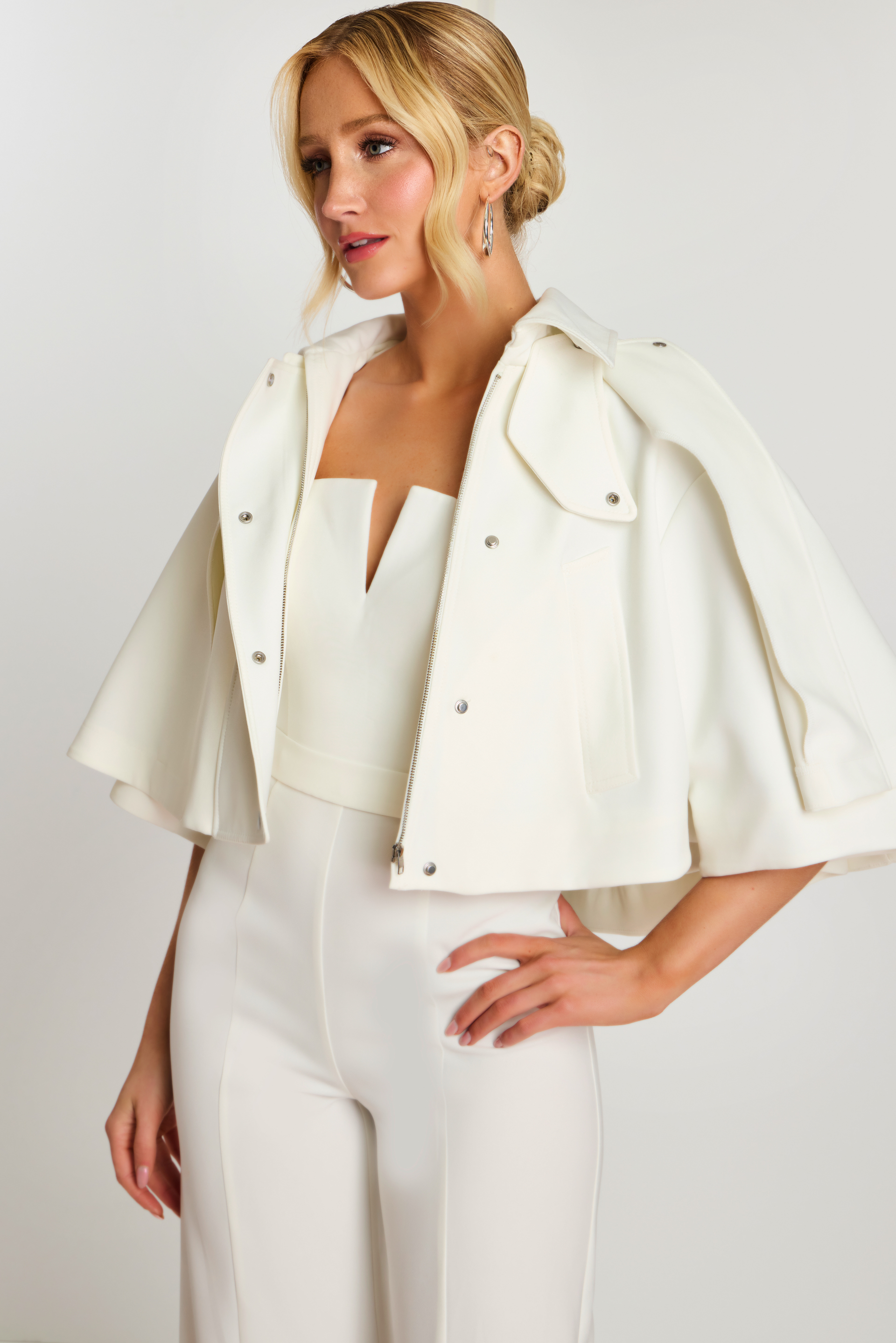 Front view of strapless V-notch white jumpsuit with jacket in hand