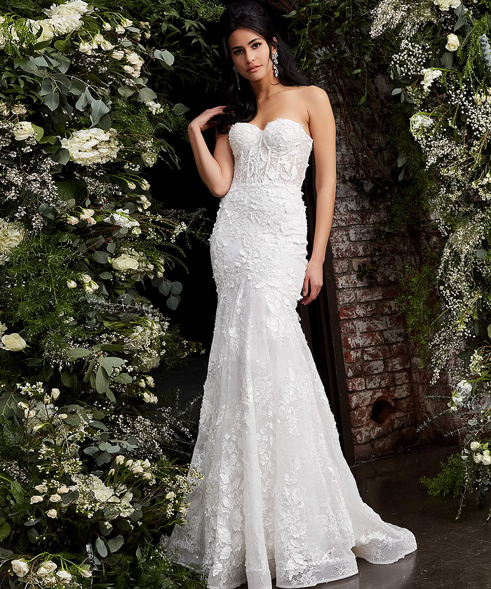 Model wearing JB02836 elegant white gown with lace appliqués, front view, surrounded by flowers