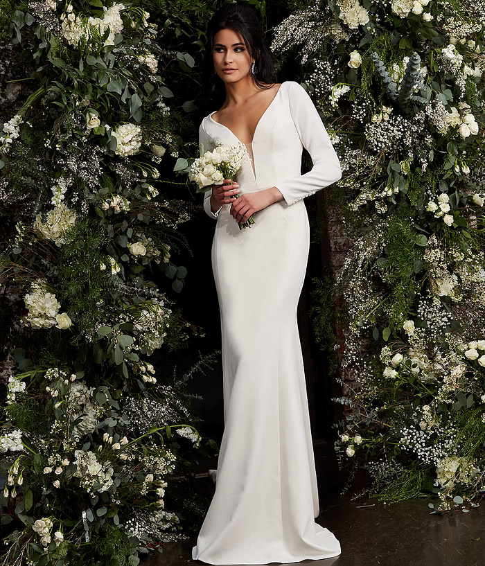 Model presenting Jovani JB06911 ivory gown with plunging neckline in a floral setting.