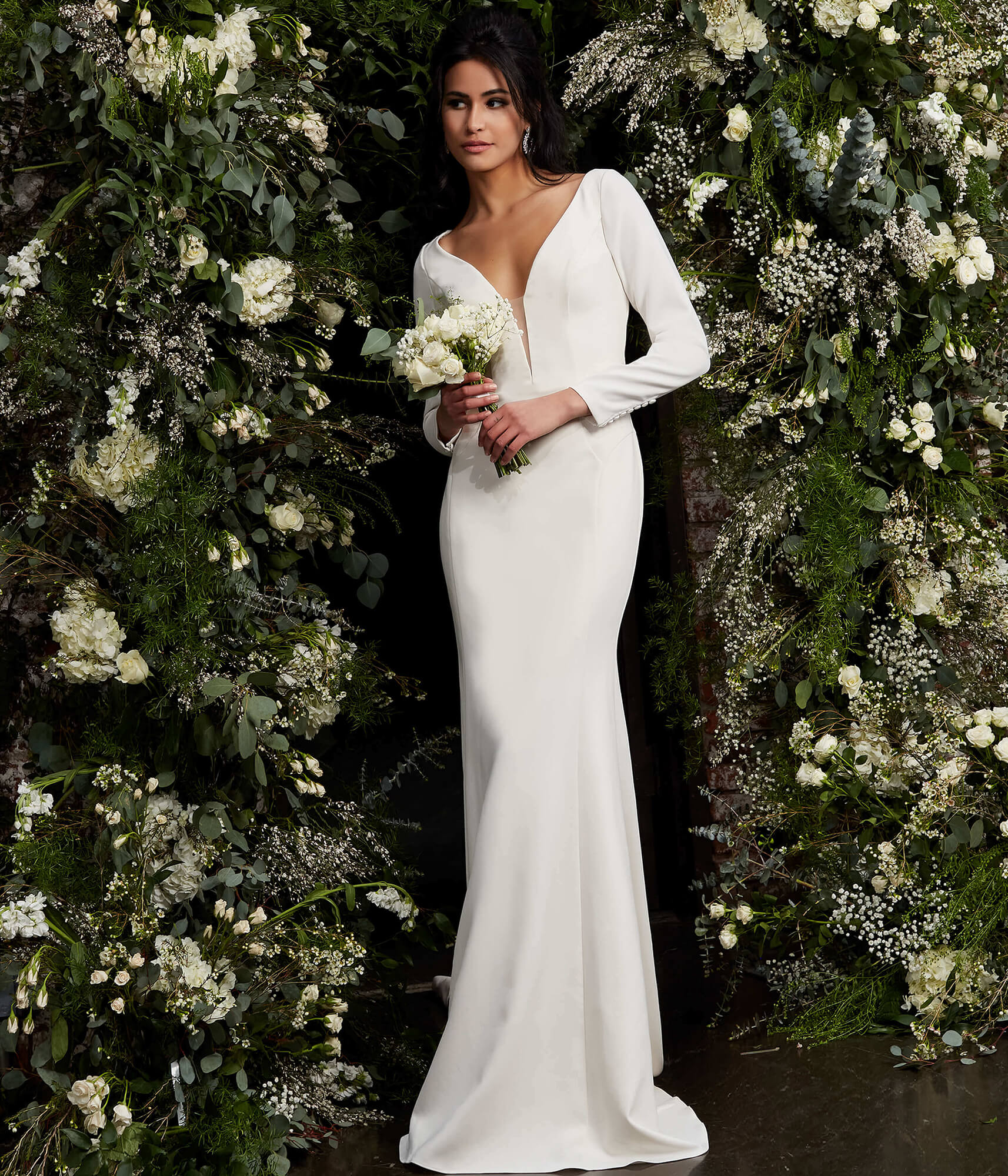 Model presenting Jovani JB06911 ivory gown with plunging neckline in a floral setting.