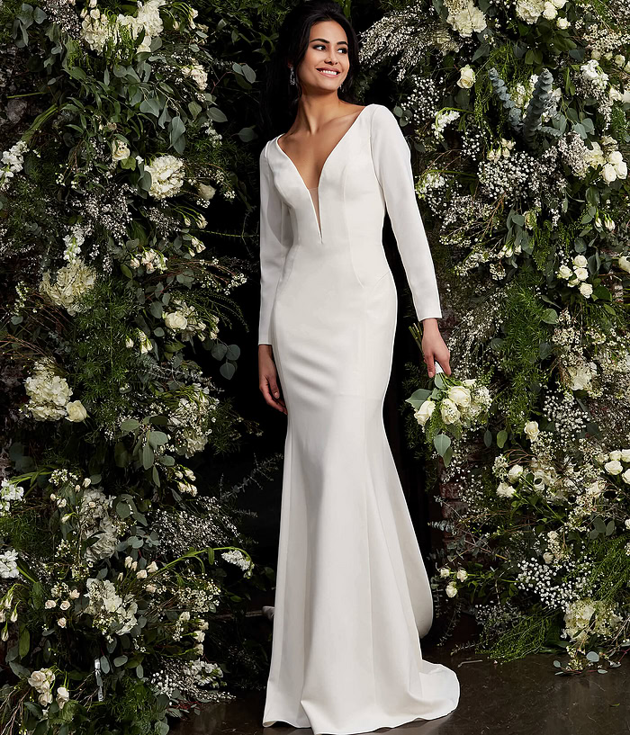 Model in Jovani JB06911 ivory gown with long sleeves and plunging neckline.