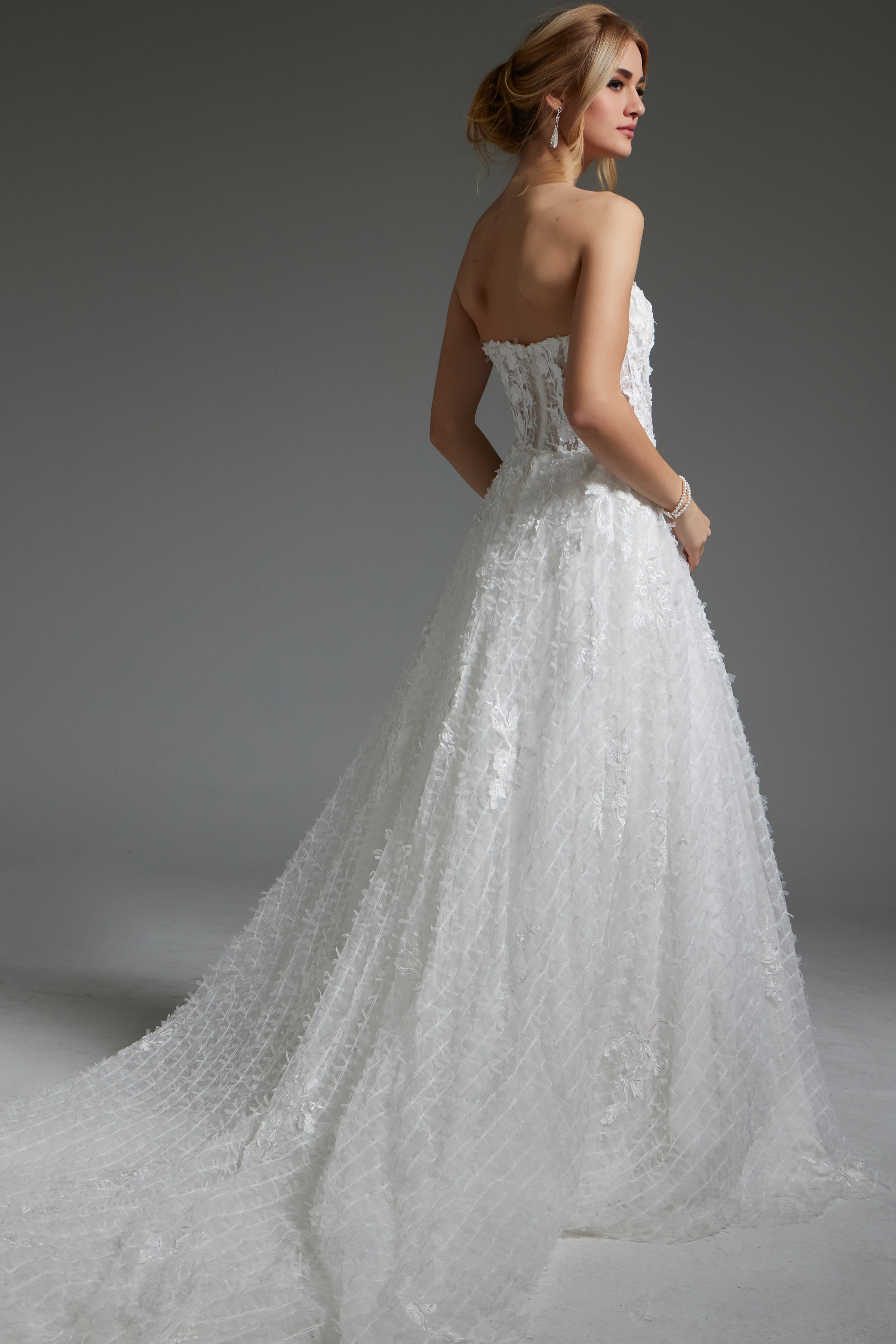 Model wearing Jovani JB07165 white gown with sheer back and floral details, back view.
