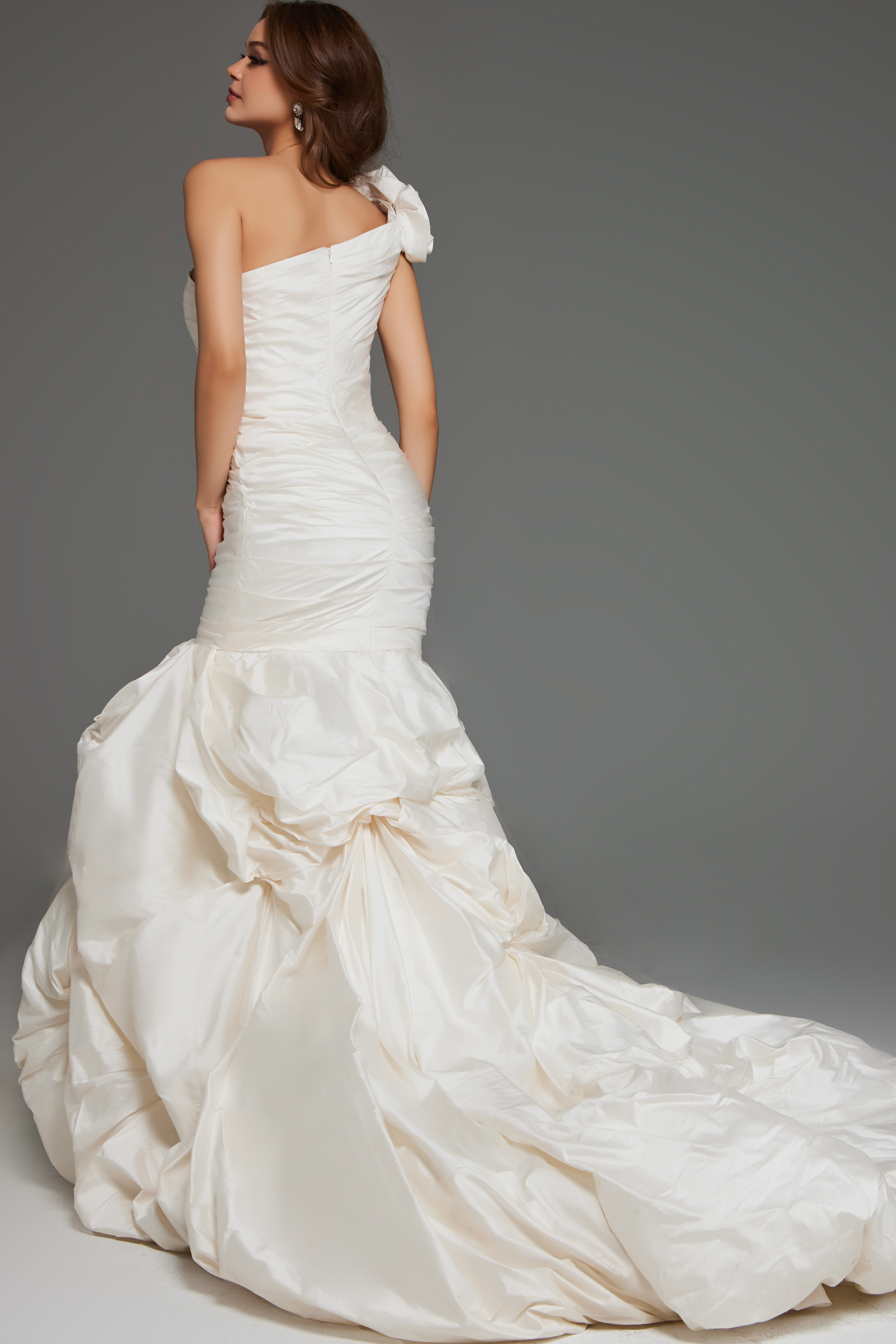 Model wearing Jovani 07179 white gown with one-shoulder neckline and mermaid silhouette, back view.