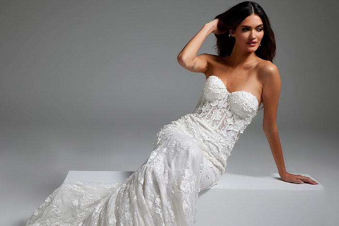 Model in Jovani JB07583 white gown sitting, showing detailed lace pattern and fit.