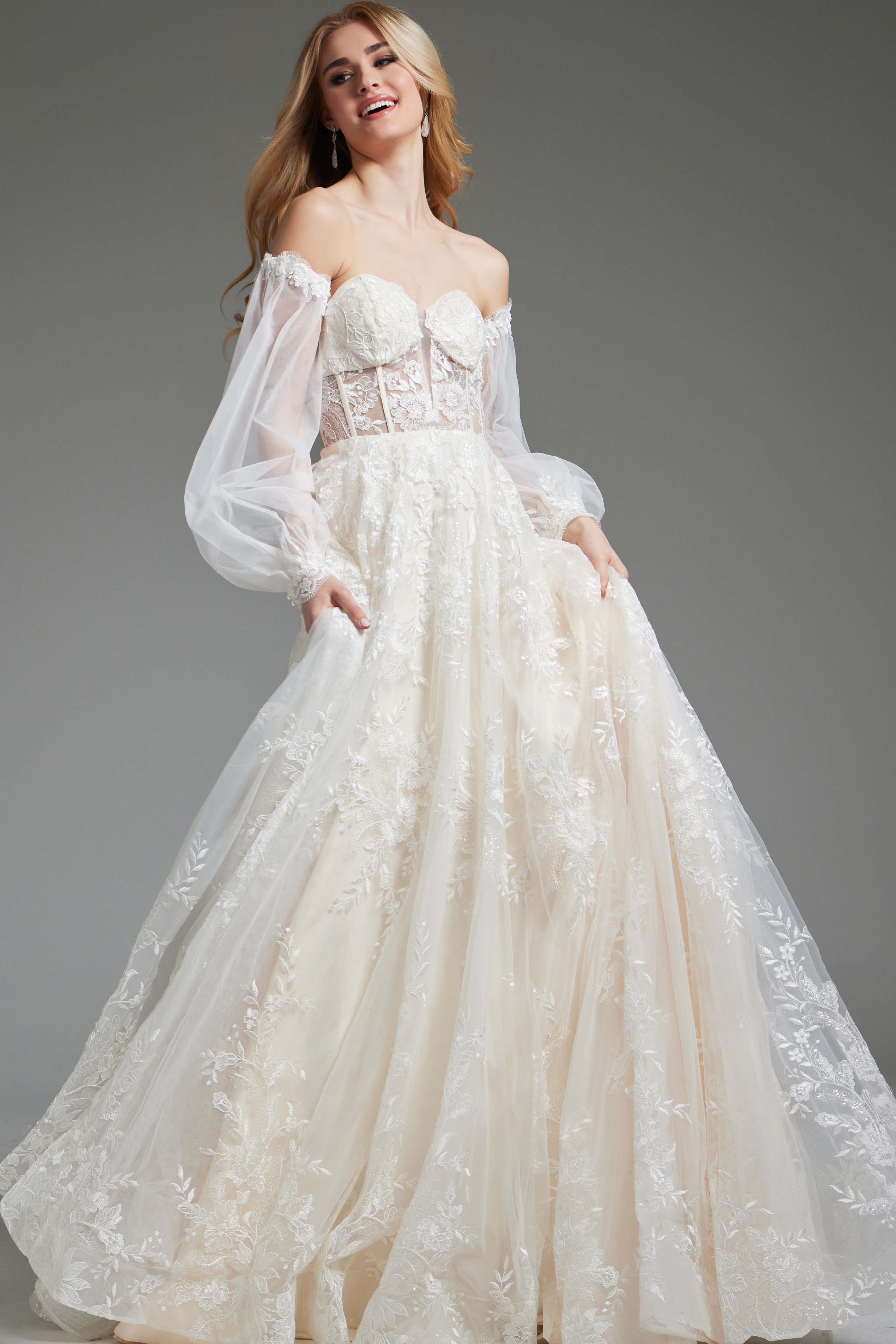 Model showcasing Jovani JB220004 ivory gown with sheer sleeves and floral details, front view.