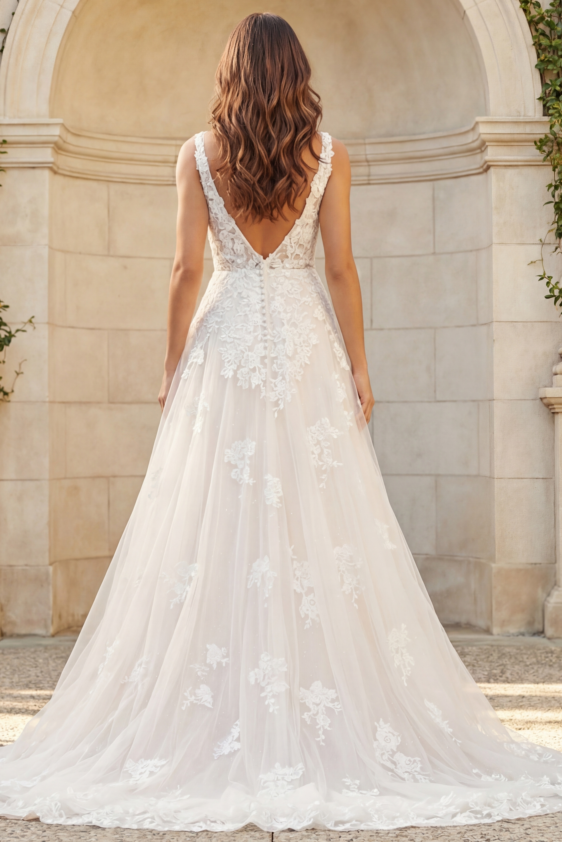 Back view of a lace A-line bridal gown with V-back, floral appliqués, and soft tulle train.