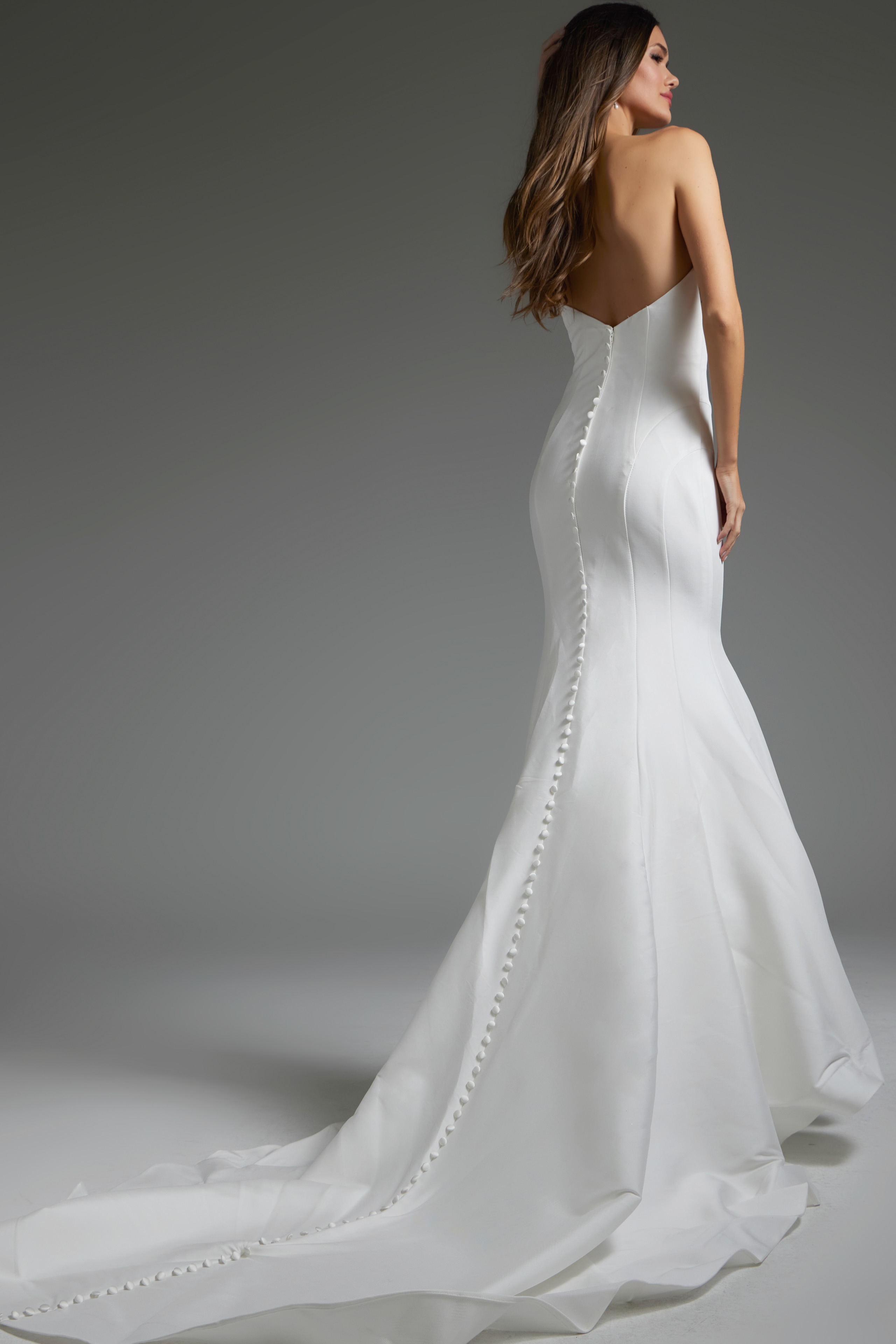 Back view of Jovani JB24282 showcasing the buttoned train of the white mermaid dress.