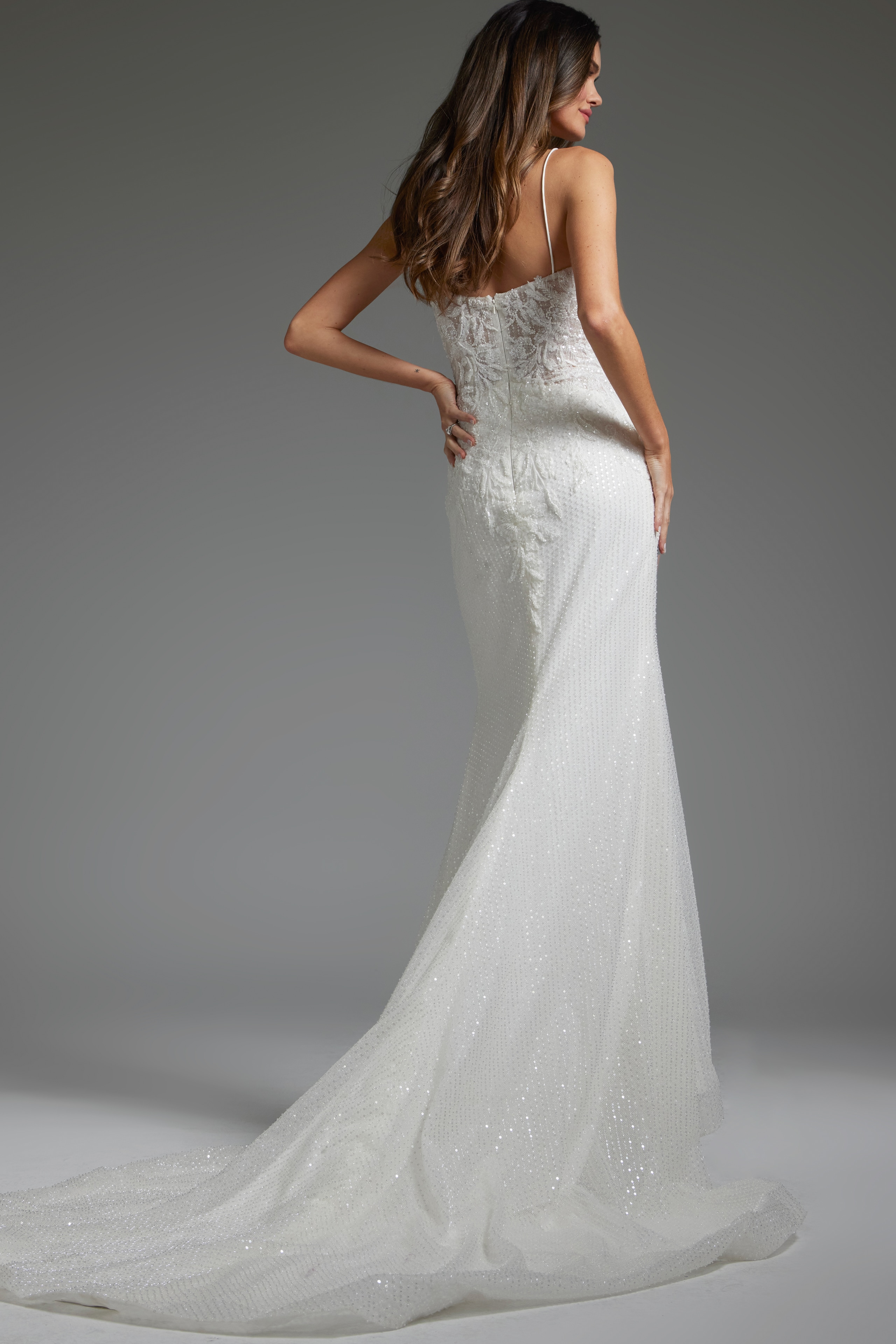 Model showcasing the back of Jovani JB40639, an ivory gown with lace details and a subtle flair.